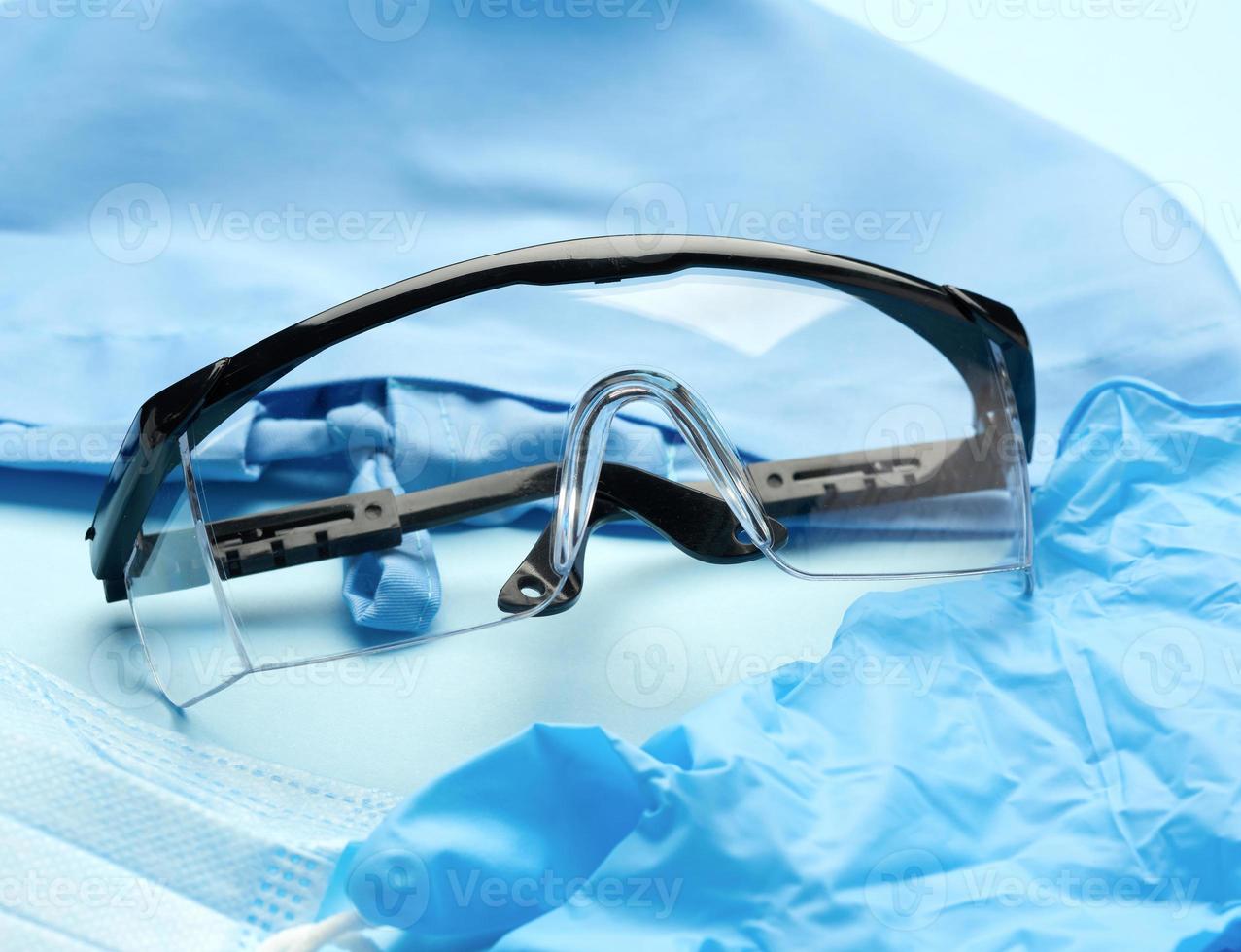 óculos de plástico protetores e máscaras descartáveis em um fundo azul foto