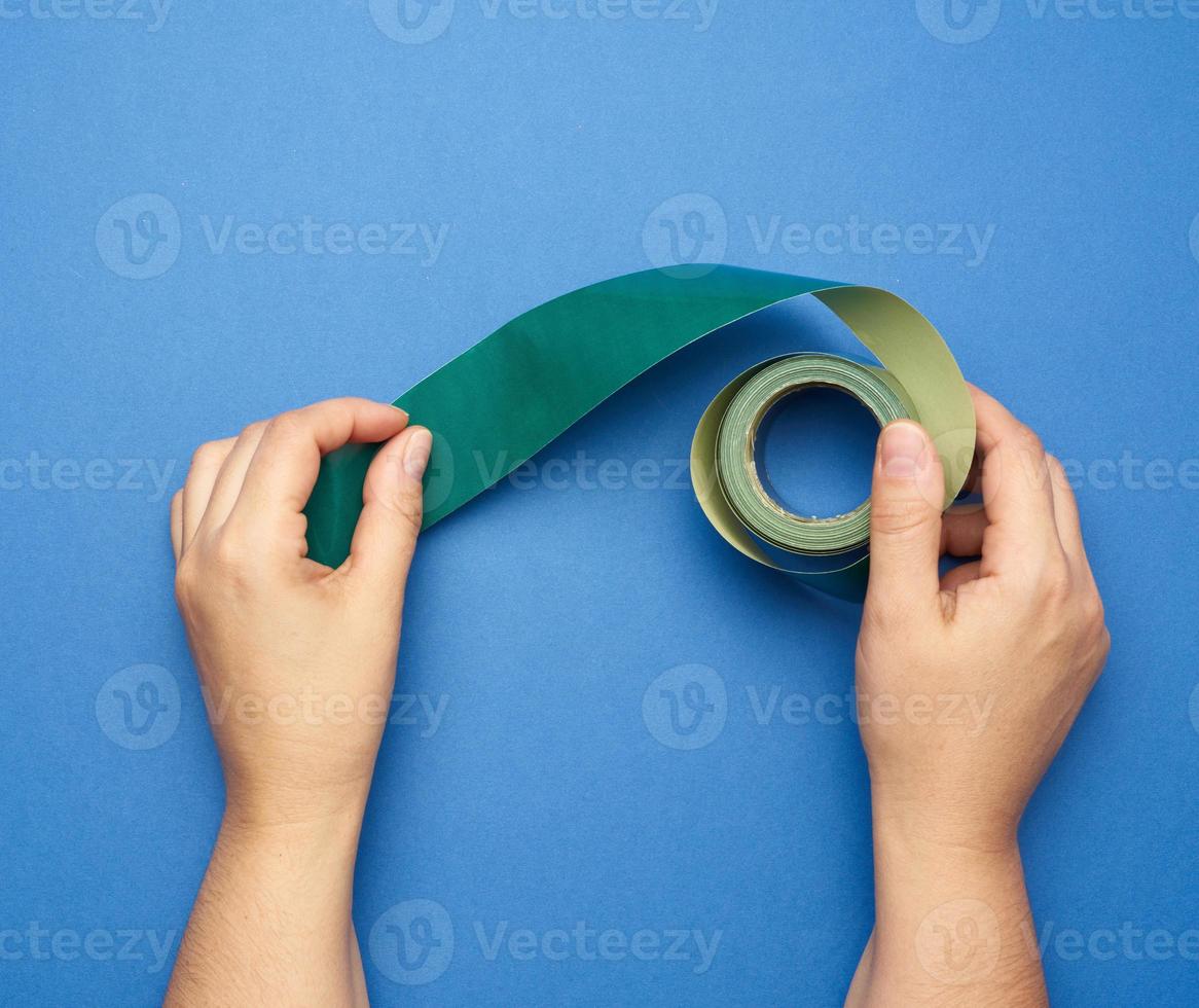 mão segure a fita adesiva de papel enrolado verde foto