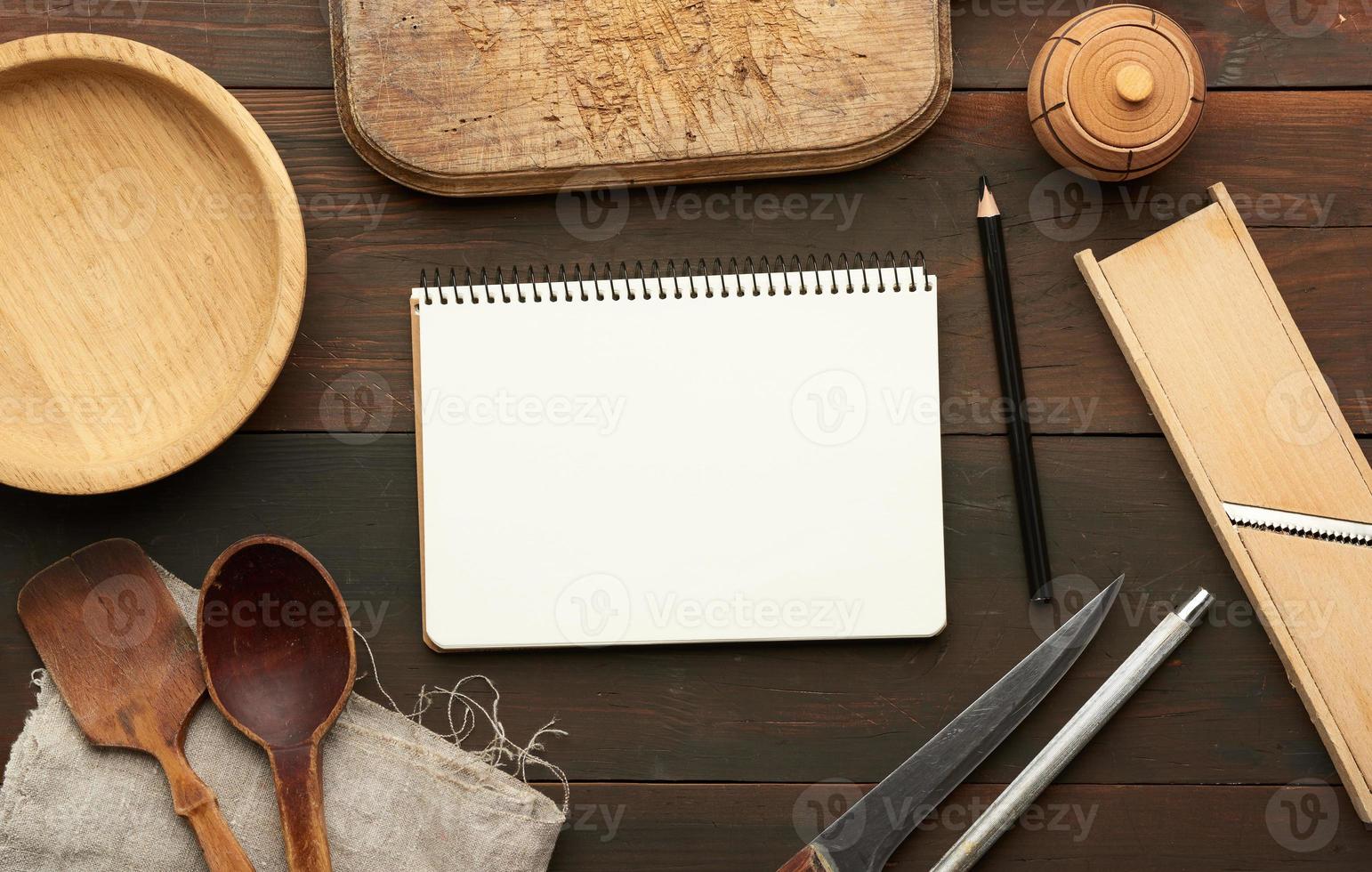 caderno aberto com lençóis brancos em branco e utensílios de cozinha na mesa de madeira marrom foto