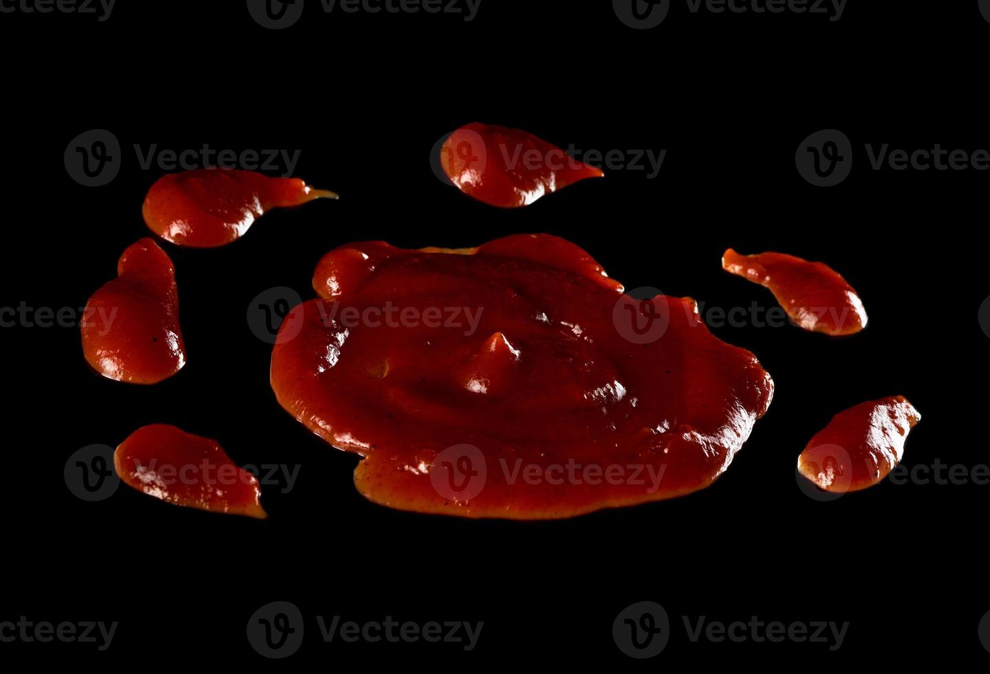 gotas de ketchup de tomate derramado com especiarias isoladas em fundo preto foto
