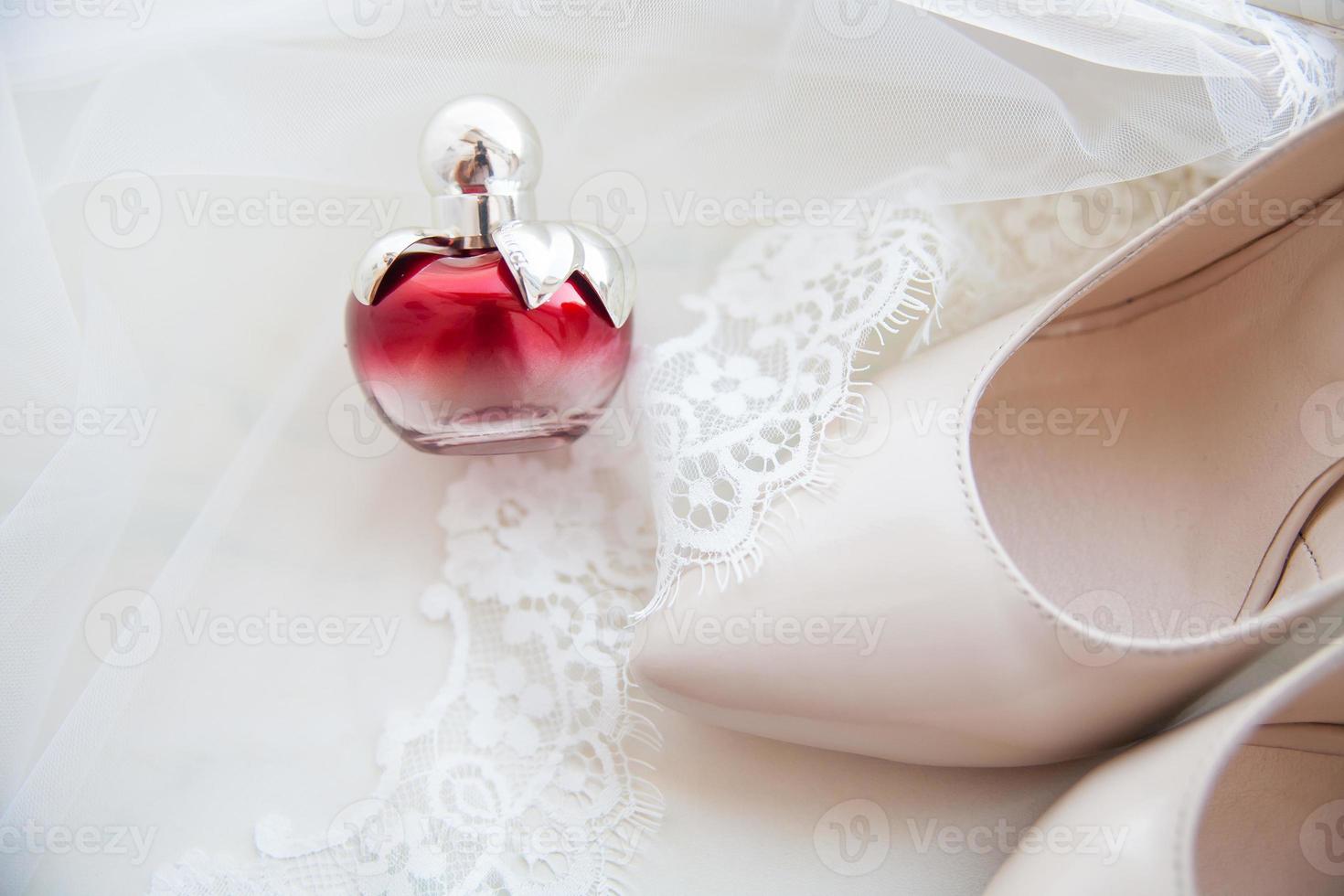 lindos acessórios de casamento. sapatos de noiva, perfumes em um véu branco foto