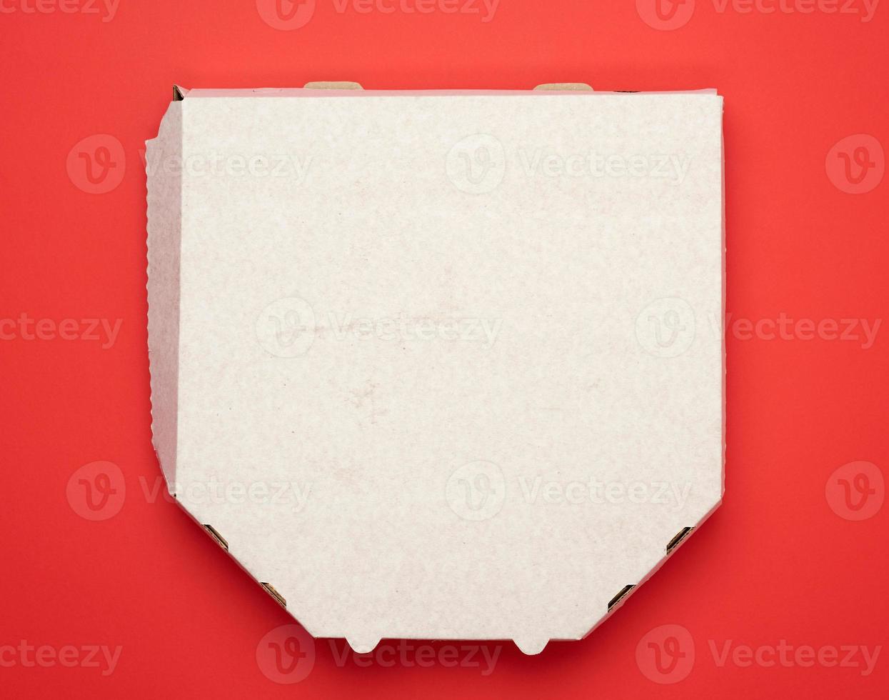 caixa de pizza branca de papelão quadrado sobre fundo vermelho foto