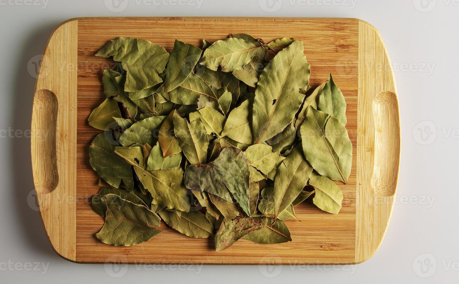 folha de louro seca aromática de especiarias. tempero aromático para comida. fundo de folha de louro seca em uma placa de cozinha de madeira foto