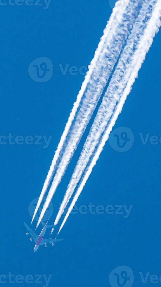 avião de quatro motores durante o vôo em alta altitude com trilhas de condensação foto