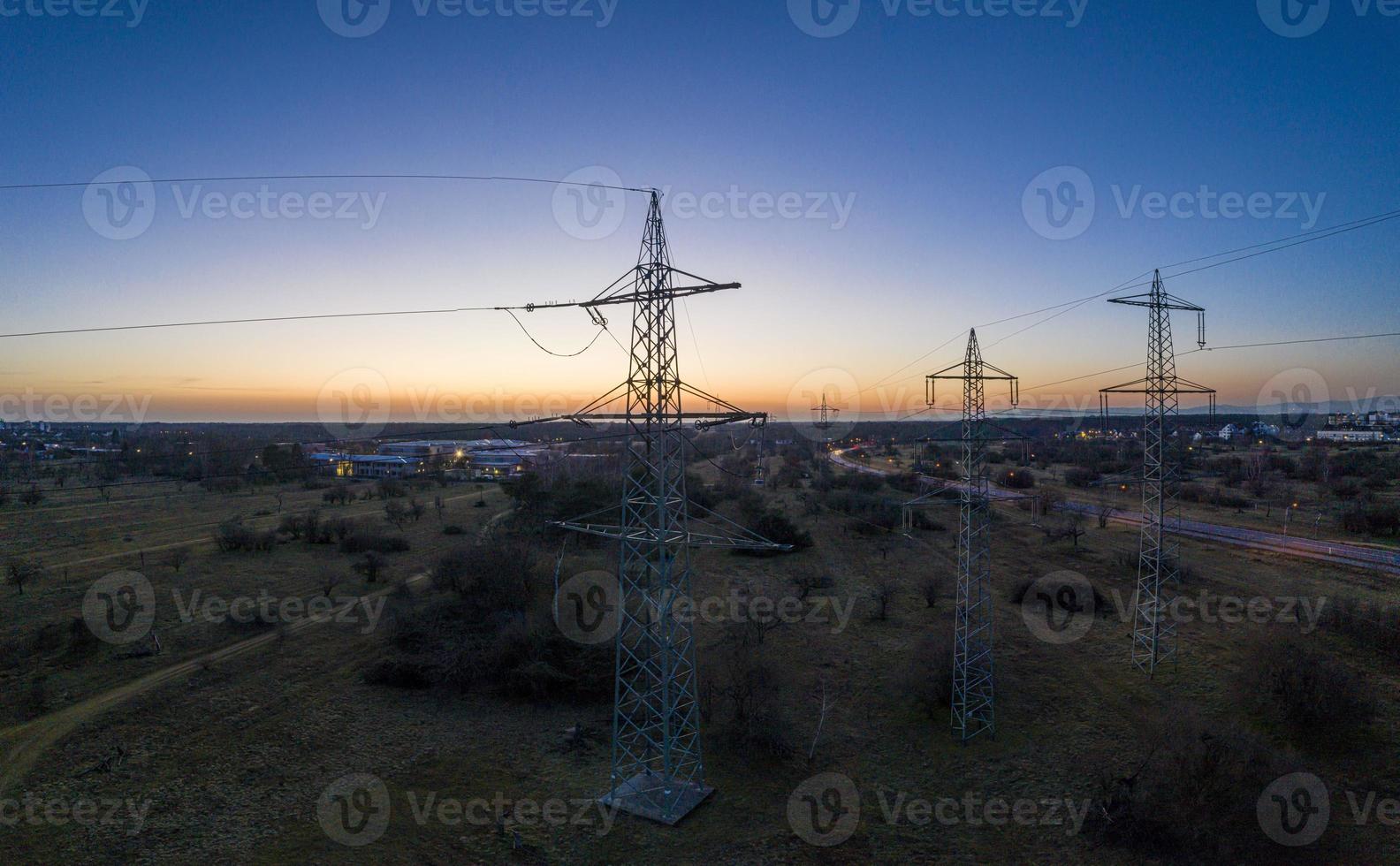 imagem panorâmica de postes de energia contra espetacular pôr do sol vermelho ao entardecer com céu sem nuvens foto