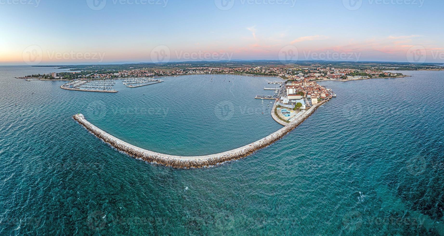 panorama drone da cidade costeira croata umag tirada durante o pôr do sol acima da entrada do porto com quebra-mar foto