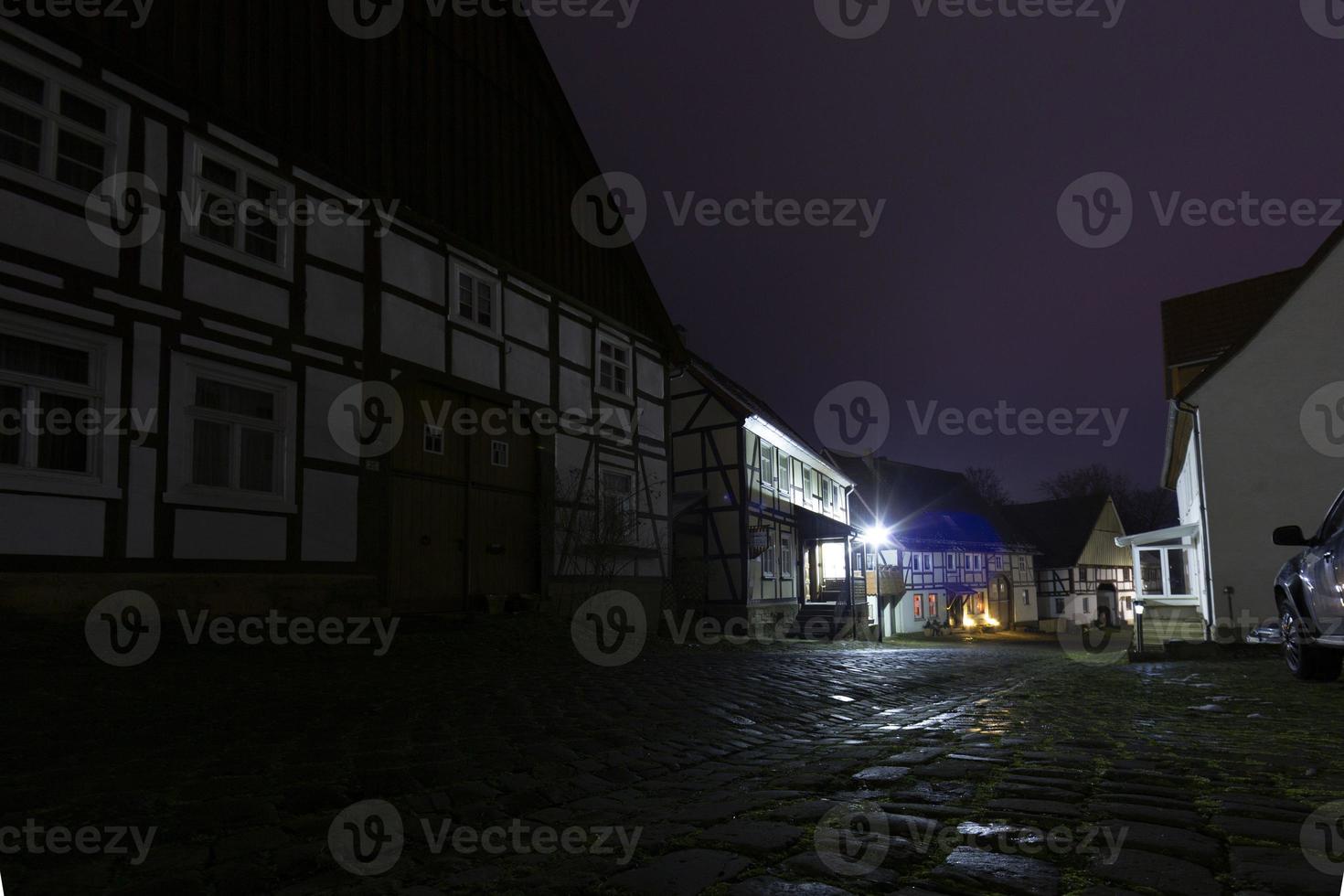 cena noturna de uma antiga cidade alemã com casas de studwork e rua de paralelepípedos em tempo úmido foto