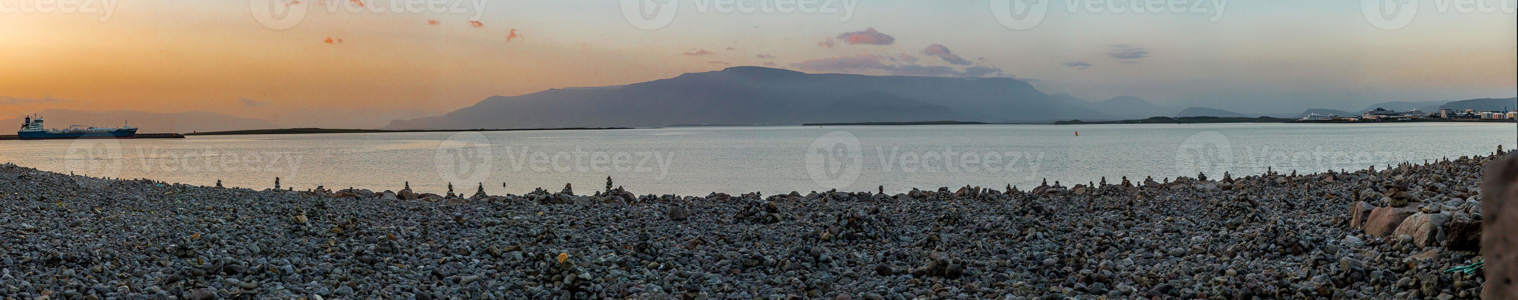 imagem panorâmica do porto de reykjavik com praia pedregosa ao pôr do sol no verão foto