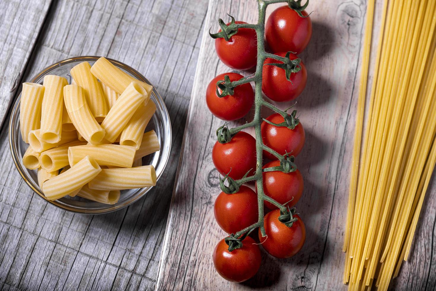 tomate cereja e macarrão fresco em uma base de madeira foto