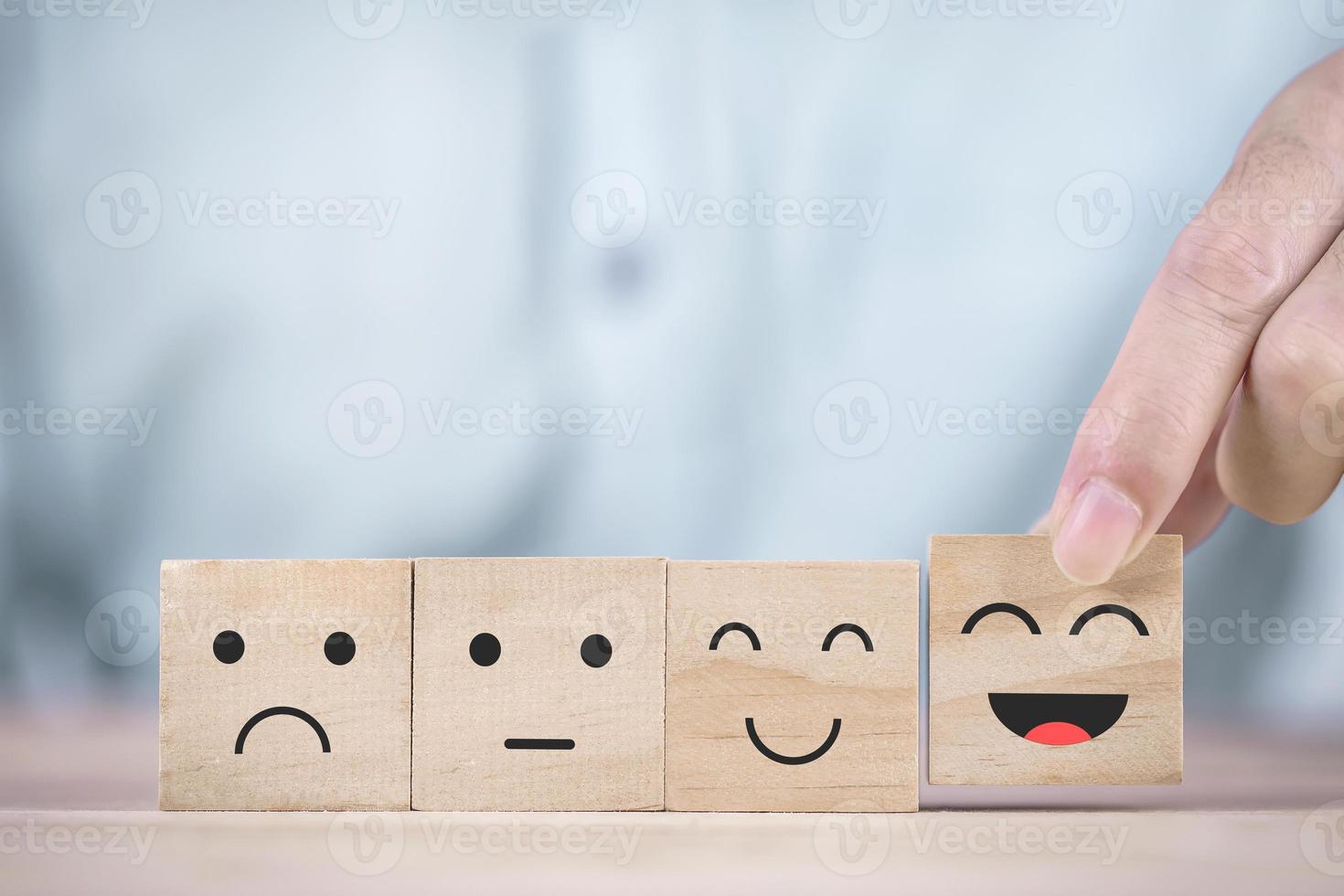 empresário escolhe um símbolo de rosto sorridente feliz no bloco de madeira, serviços e conceito de pesquisa de satisfação do cliente foto