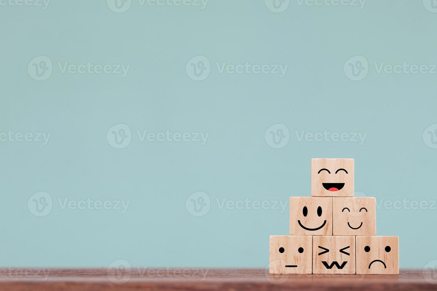 símbolo feliz de rosto sorridente no bloco de madeira, serviços e conceito de pesquisa de satisfação do cliente foto