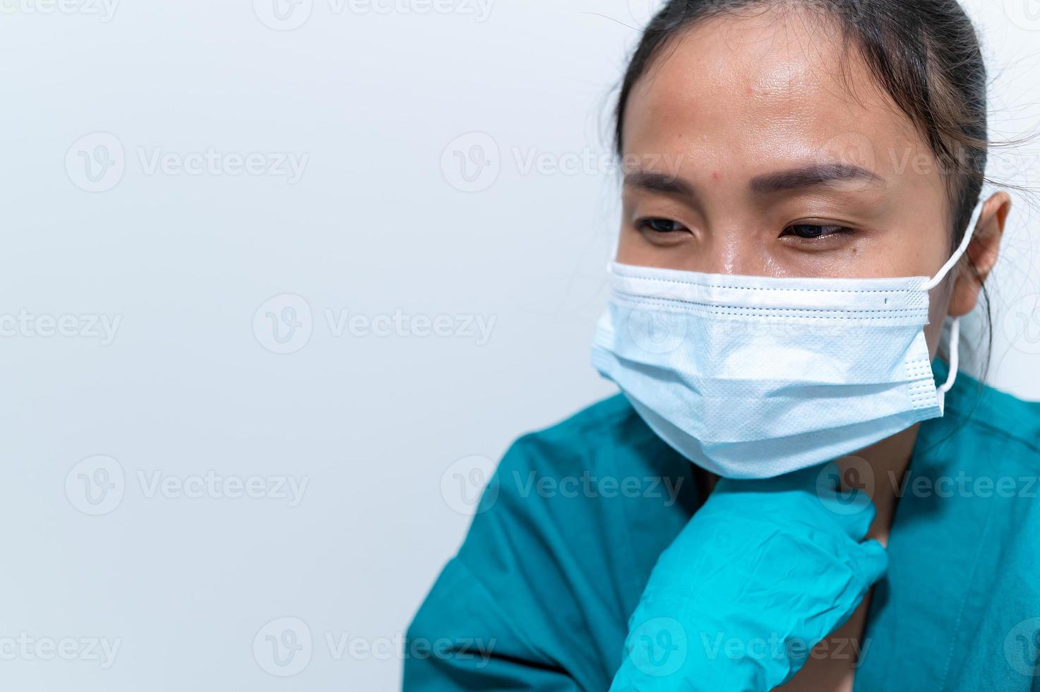 Enfermeira asiática deprimida cansada usa máscara facial uniforme azul senta-se no chão do hospital, jovem médica estressada pelo trabalho duro foto