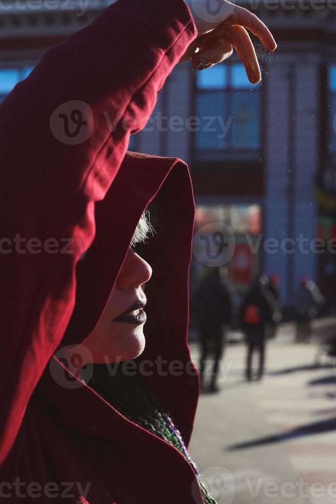 feche a mulher de fantasia com capuz vermelho espalhando pó mágico sobre a foto do retrato da cabeça