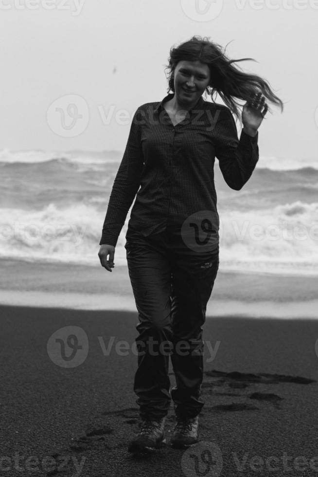 turista na praia negra em fotografia cênica monocromática de vento forte foto