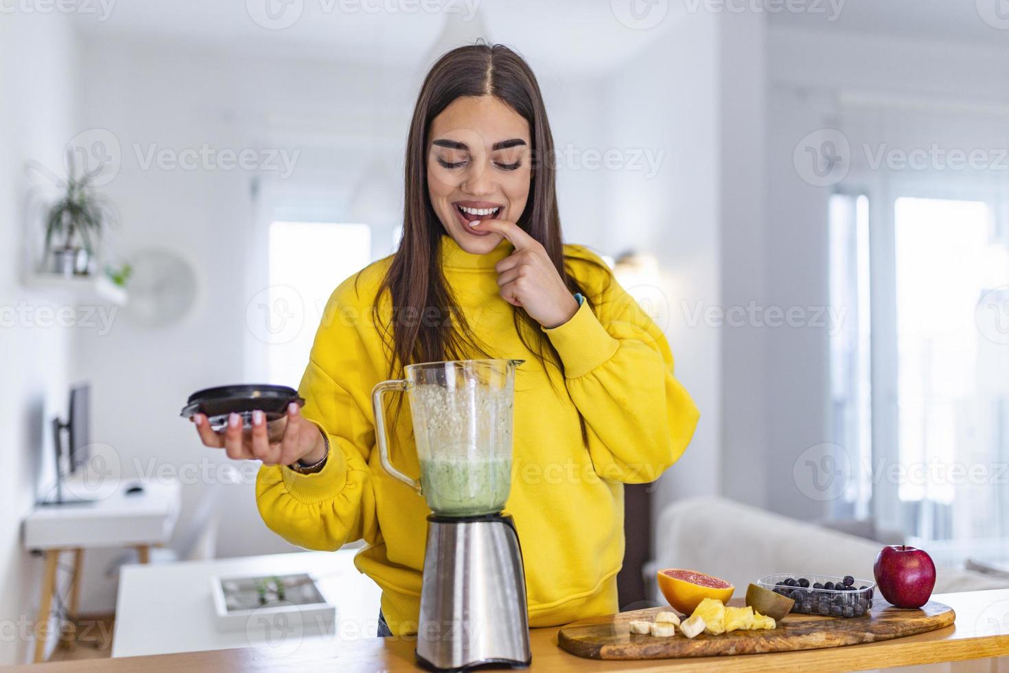 mulher saudável gosta de fazer limpeza de desintoxicação de vegetais verdes e smoothie de frutas verdes com liquidificador na cozinha em casa. estilo de vida saudável. garota bonita degustação de smoothie foto