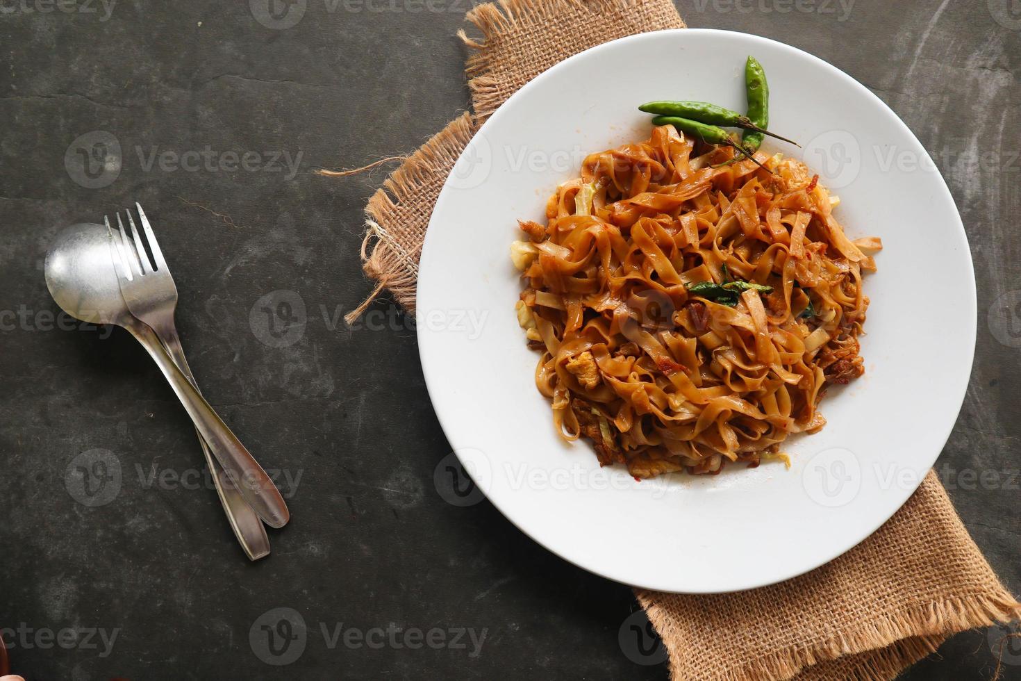 kwetiau goreng é chinês indonésio prato de macarrão de arroz plano frito feito de kwetiau, frito em óleo de cozinha com alho, cebola, carne, frango, camarão frito, caranguejo e outros vegetais foto