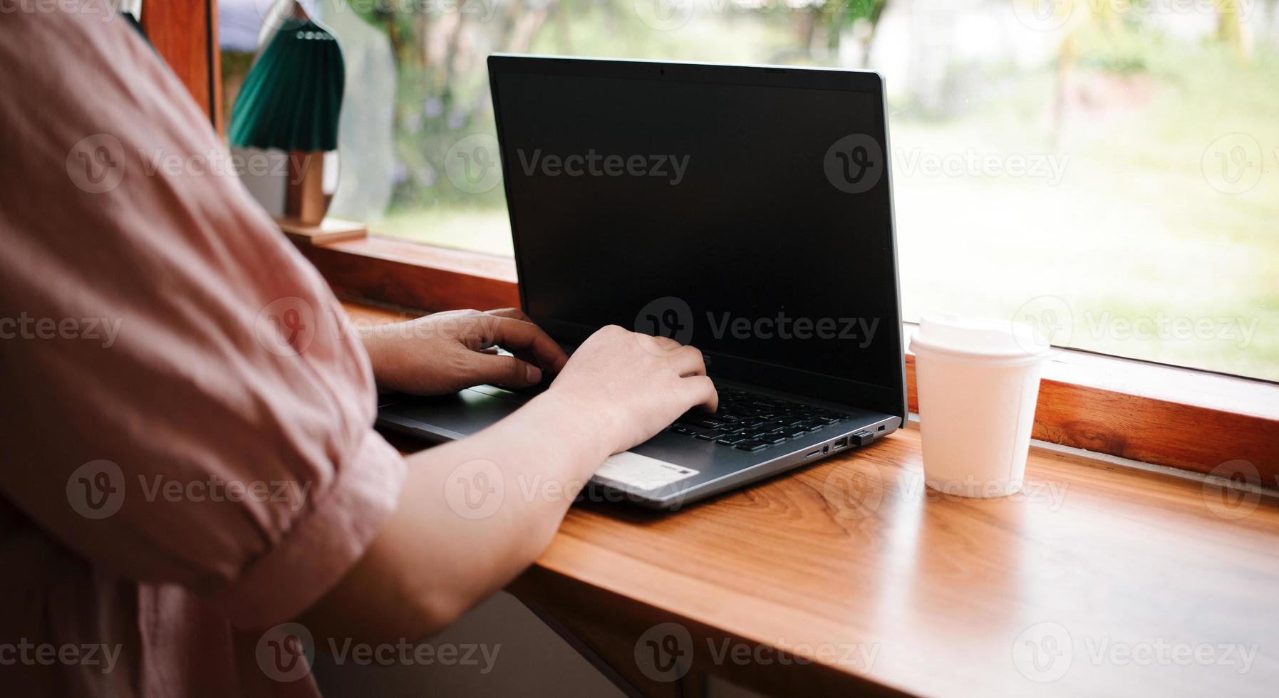 mulher de negócios trabalhando em um laptop, senhora idosa ou de meia-idade usando o conceito de computador escrevendo e-mails, comunicando-se on-line, enquanto está sentado em uma mesa em um café aconchegante. foto