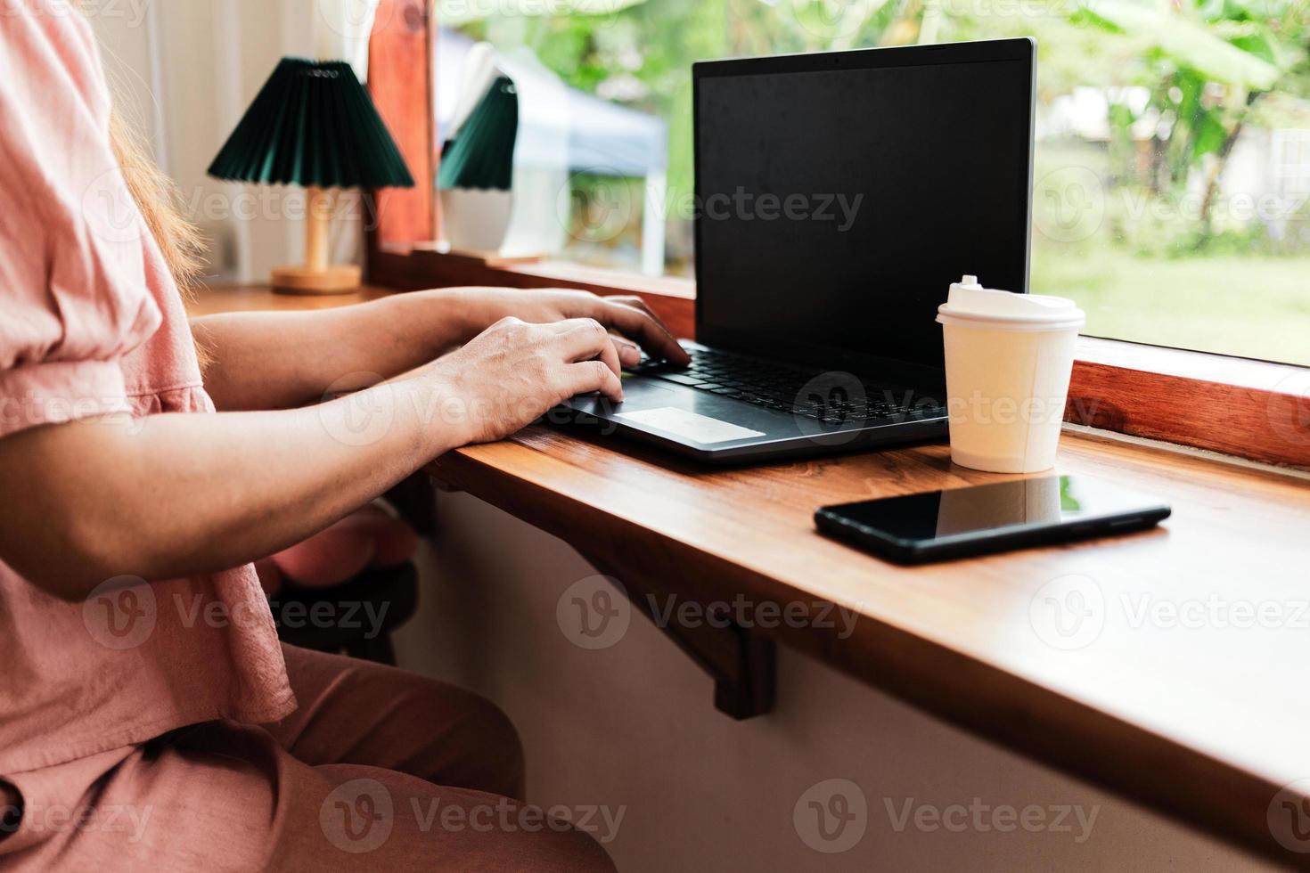 close-up das mãos da mulher digitando em um laptop.businesswoman trabalhando em um laptop, senhora usando o conceito de computador escrevendo e-mails, comunicando-se on-line, enquanto está sentado em uma mesa em um café aconchegante. foto