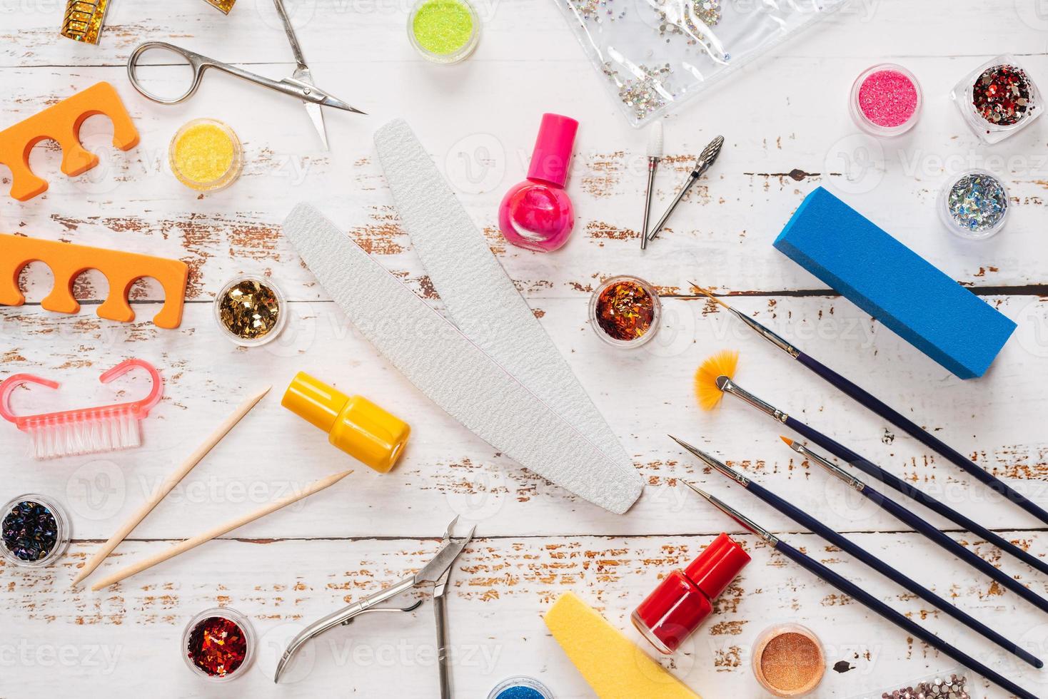 conjunto de ferramentas de manicure e esmaltes em um fundo branco de madeira. foto