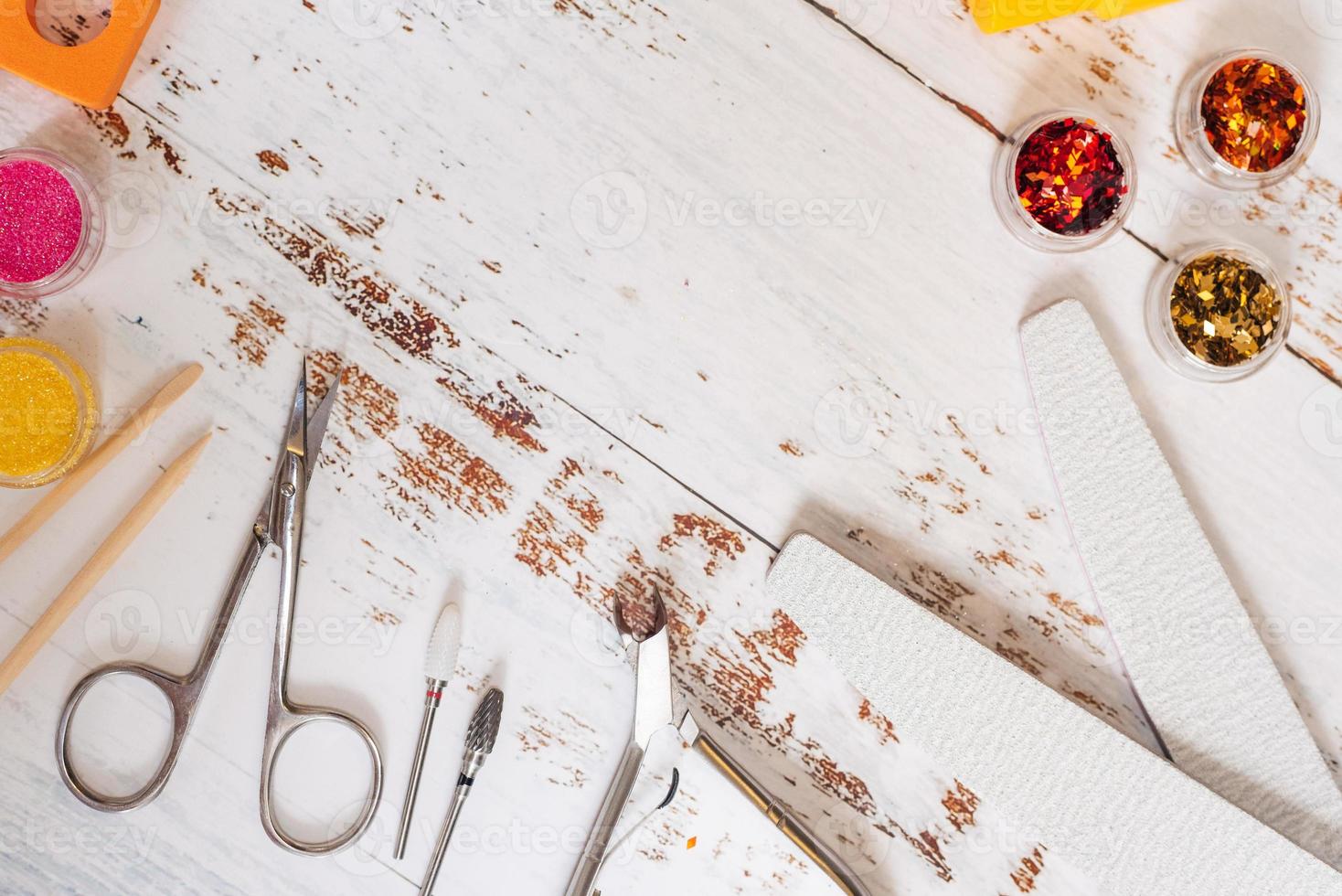 conjunto de ferramentas de manicure e esmaltes em um fundo branco de madeira. com espaço para seu texto foto