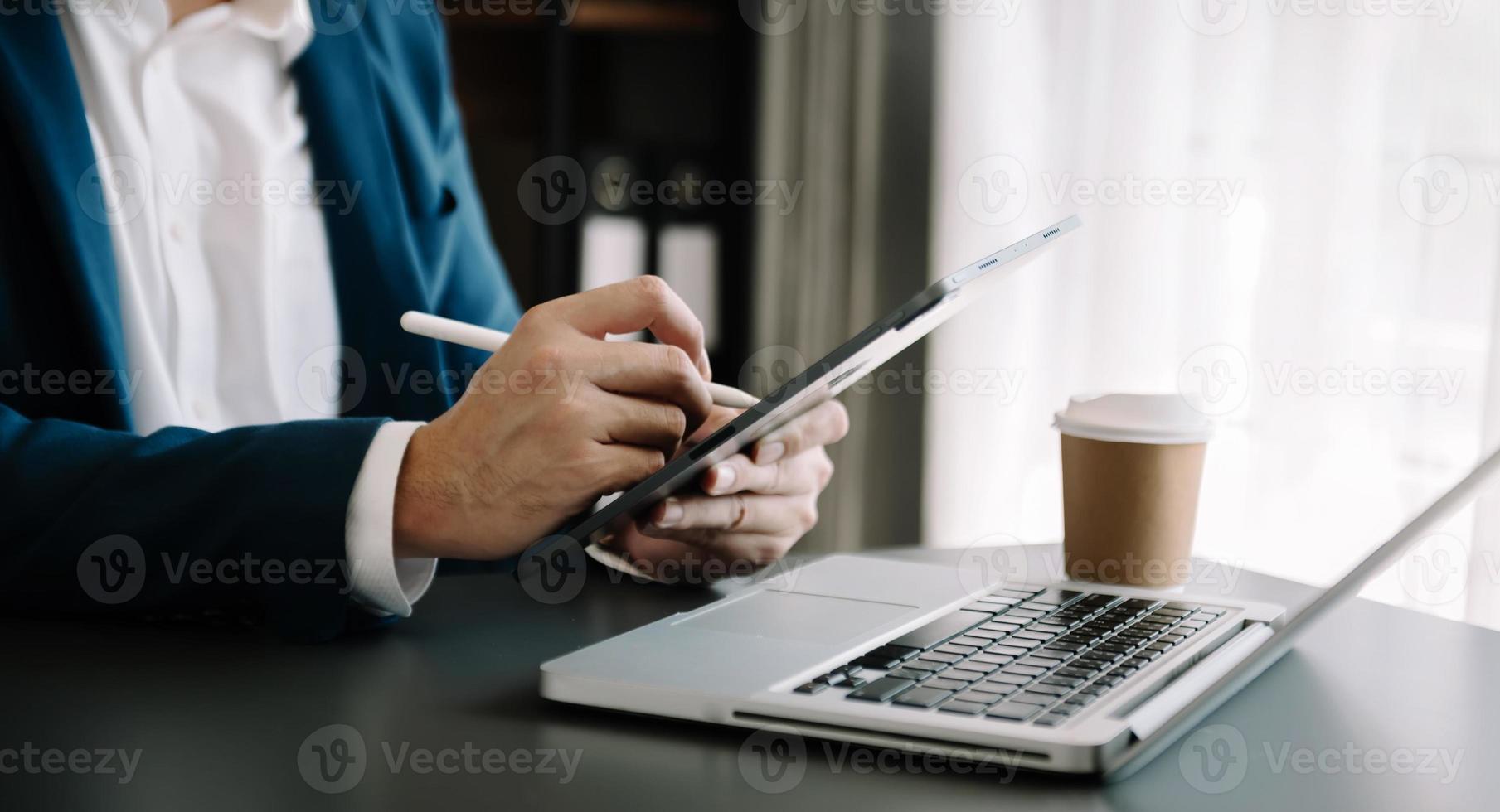 empresário trabalhando em laptop e tablet em seu local de trabalho no escritório moderno. foto