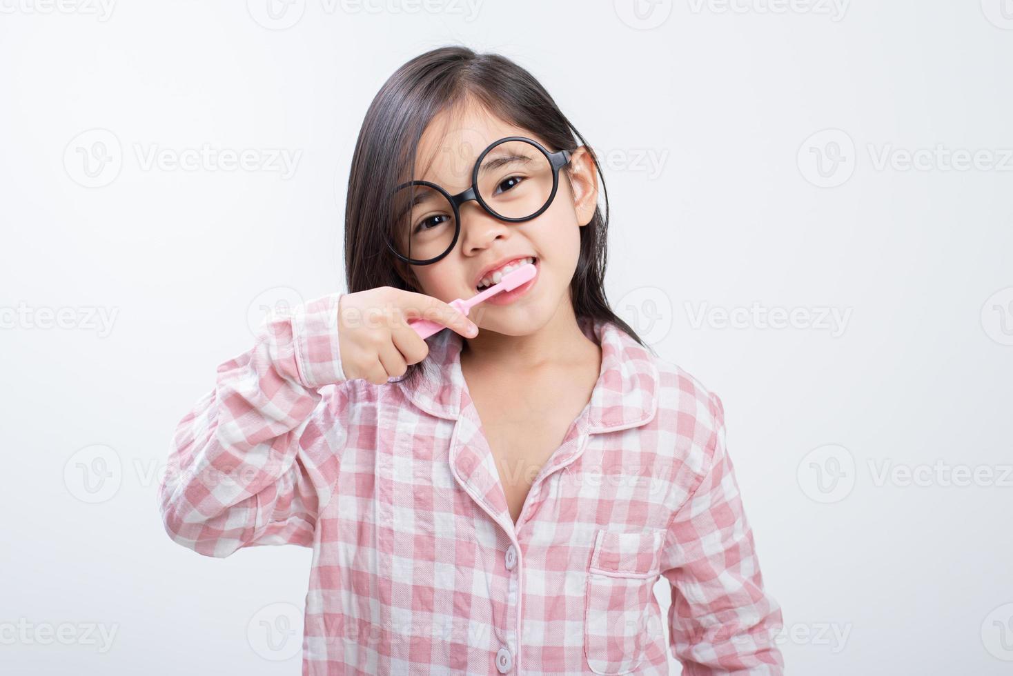 menina ásia escovando os dentes alegremente fundo branco foto