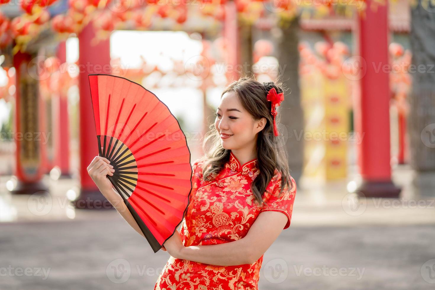 feliz Ano Novo Chinês. bela dama vestindo traje tradicional cheongsam qipao segurando ventilador no templo budista chinês. foto