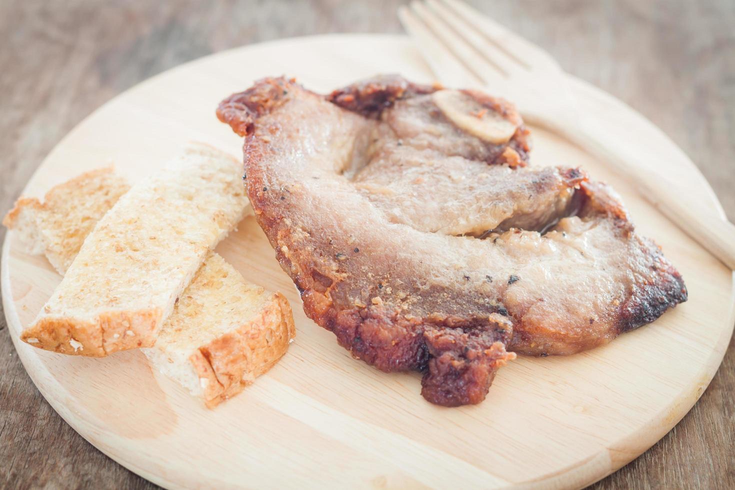 bife de porco e torradas em um prato foto