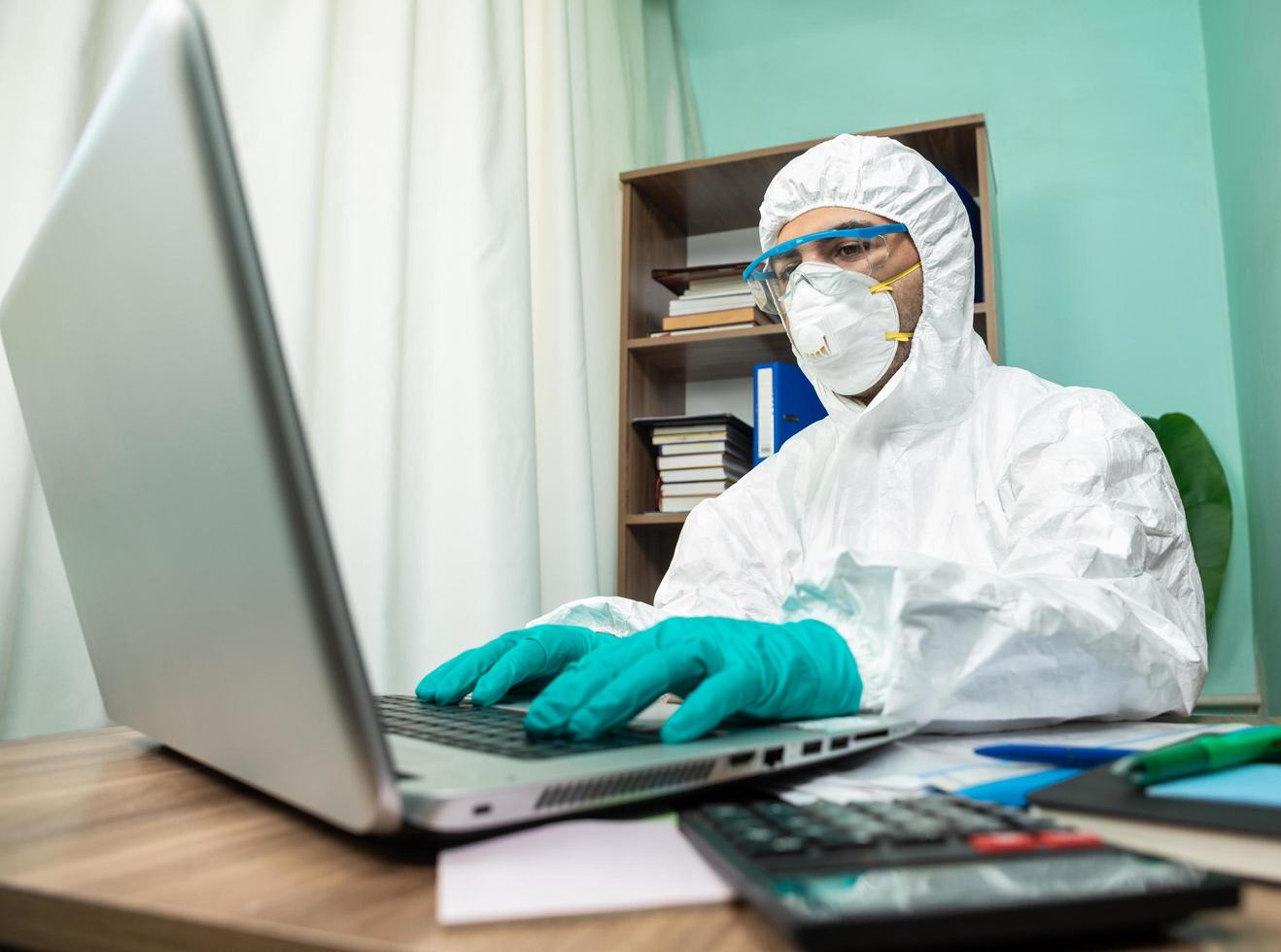 pessoa em traje de proteção trabalhando em um laptop no escritório foto