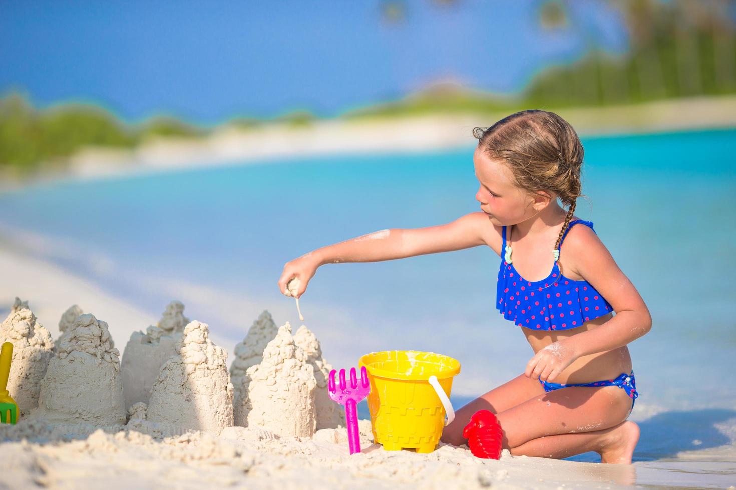 menina construindo um castelo de areia foto