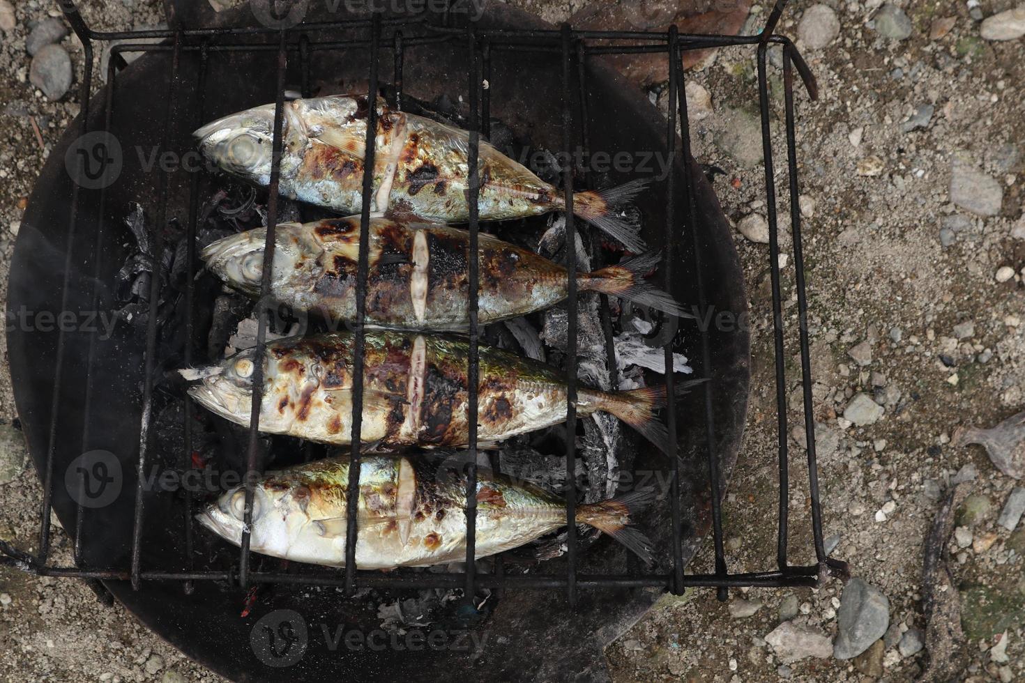 o processo de fazer peixe grelhado que é queimado sobre brasas de casca de coco foto