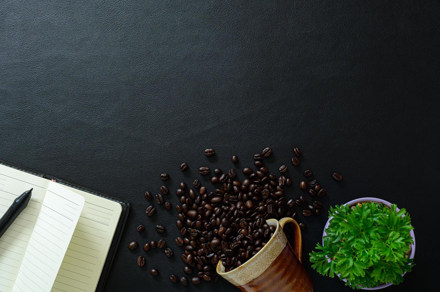 mesa preta com caderno e grãos de café foto