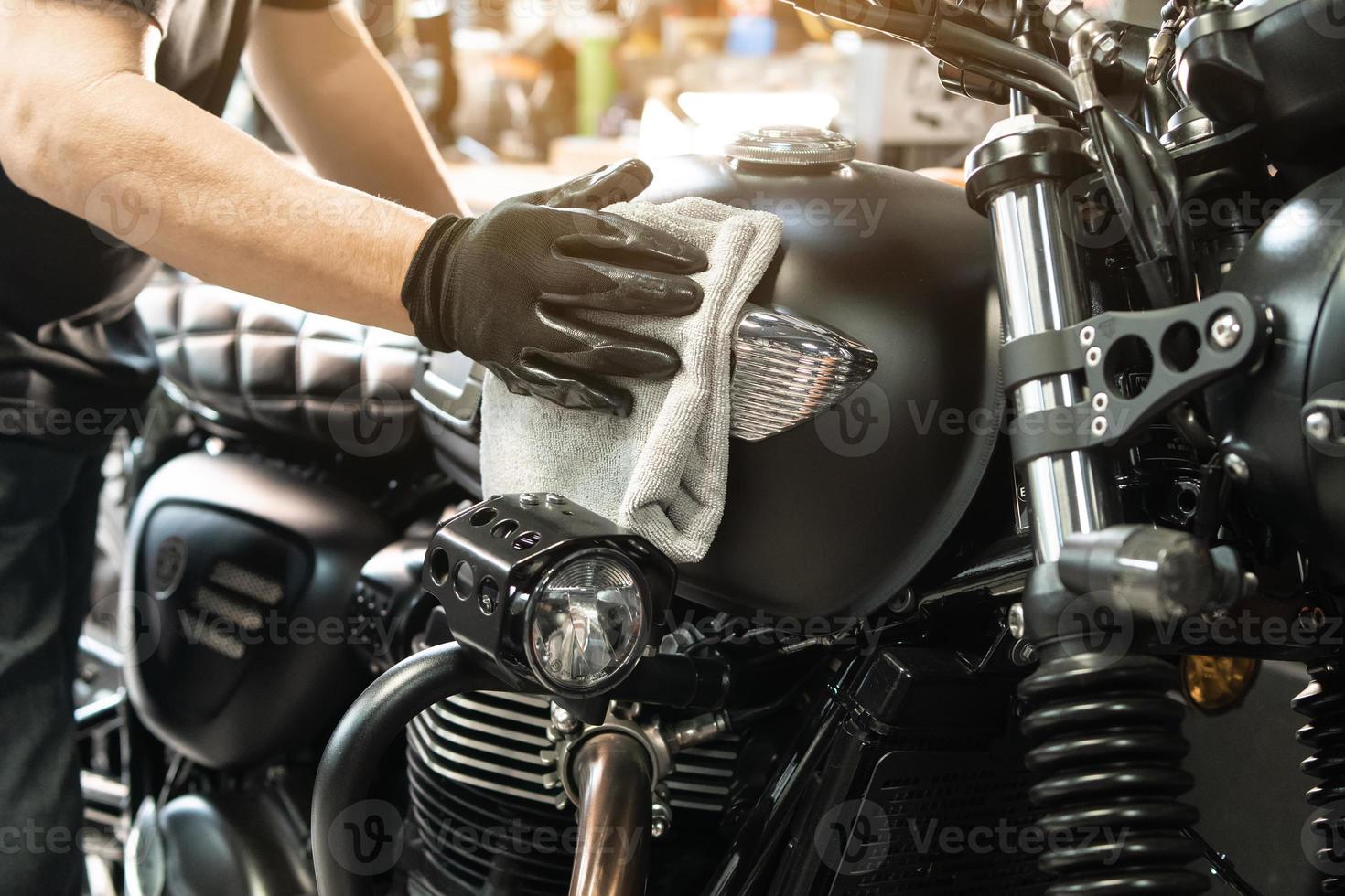 motociclista limpando motocicleta, cera polida e de revestimento no tanque de combustível na garagem. conceito de motocicleta de reparação e manutenção. foto