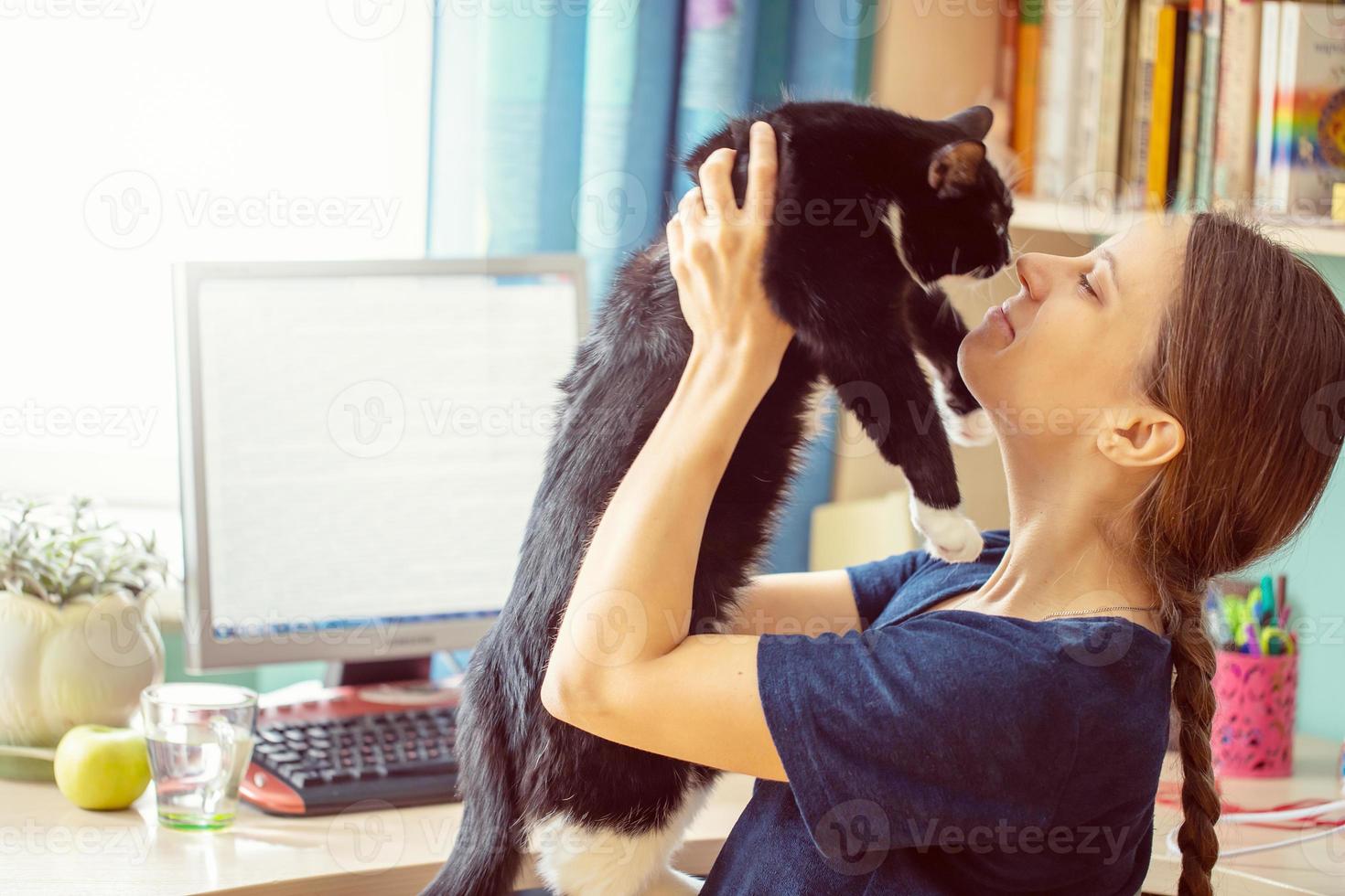 aluna estudando on-line em ambiente doméstico. jovem segurando nas mãos gato preto durante o intervalo do estudo. foco suave. foto