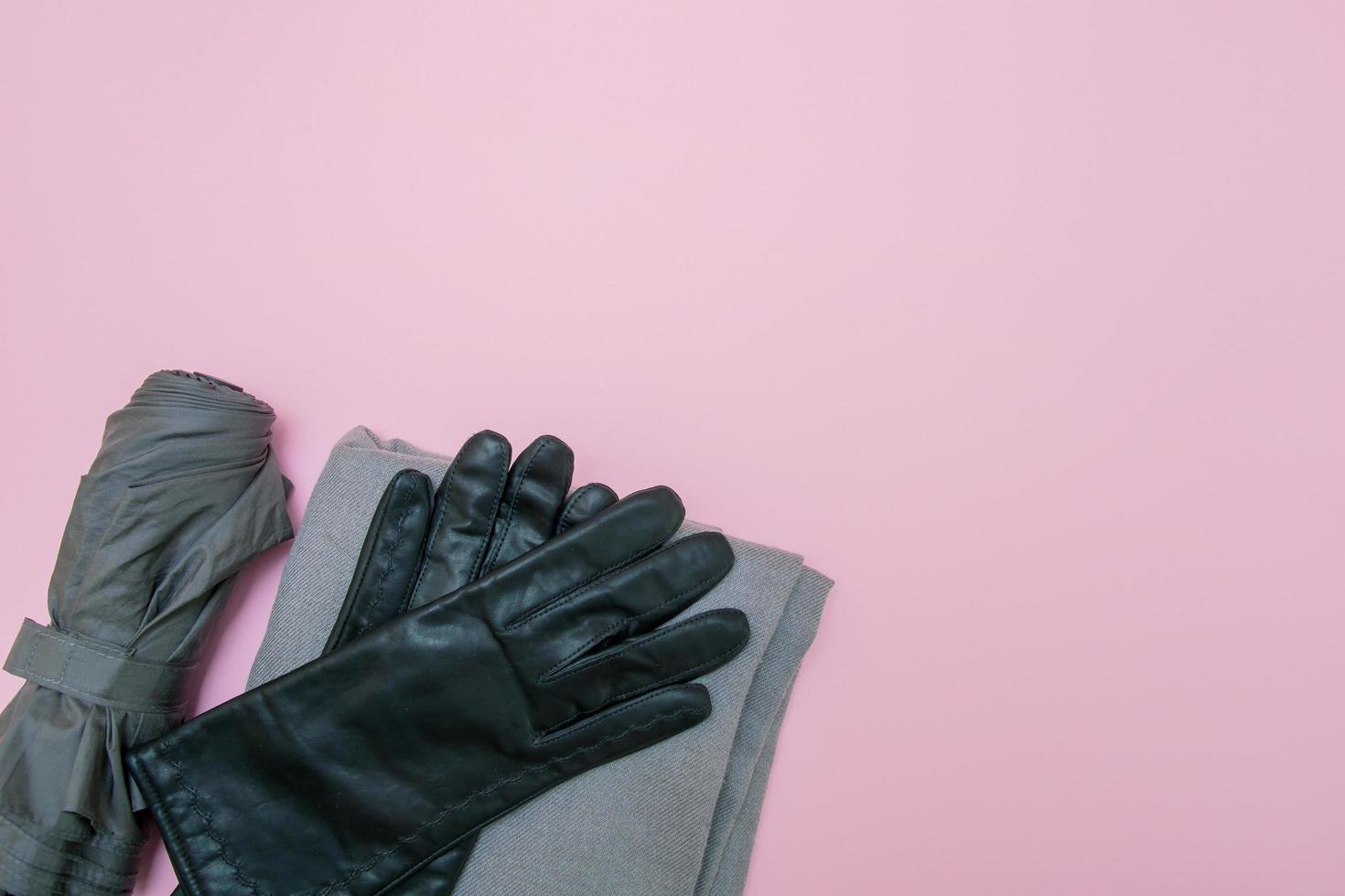 luvas cinzas, guarda-chuva e cachecol em um fundo rosa com espaço de cópia foto