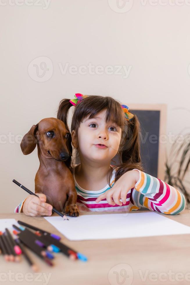 menina bonitinha desenha com seu amigo cachorro dachshund. crianças e animais. cão amigável. foto de alta qualidade