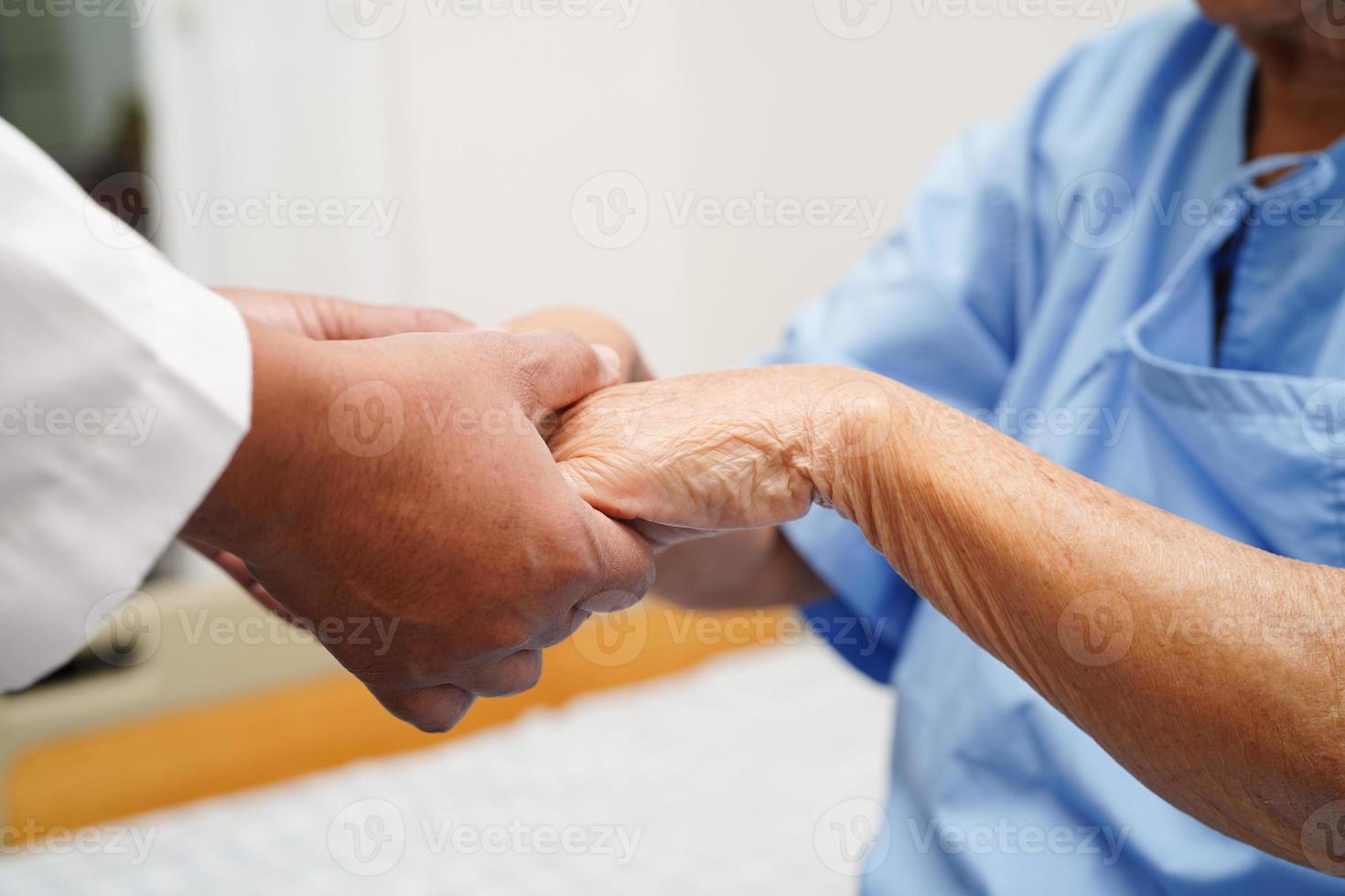 médico de mãos dadas paciente idosa asiática, ajuda e cuidados no hospital. foto
