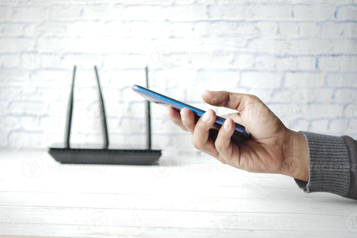 internet sem fio wi-fi e mão segurando o telefone inteligente na mesa foto