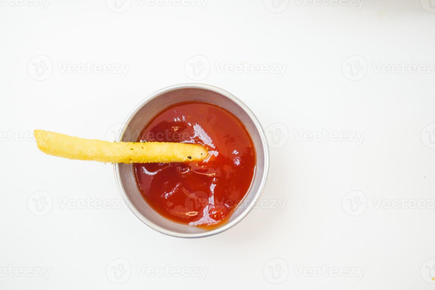 tiro de detalhe de batatas fritas bebendo molho na mesa foto