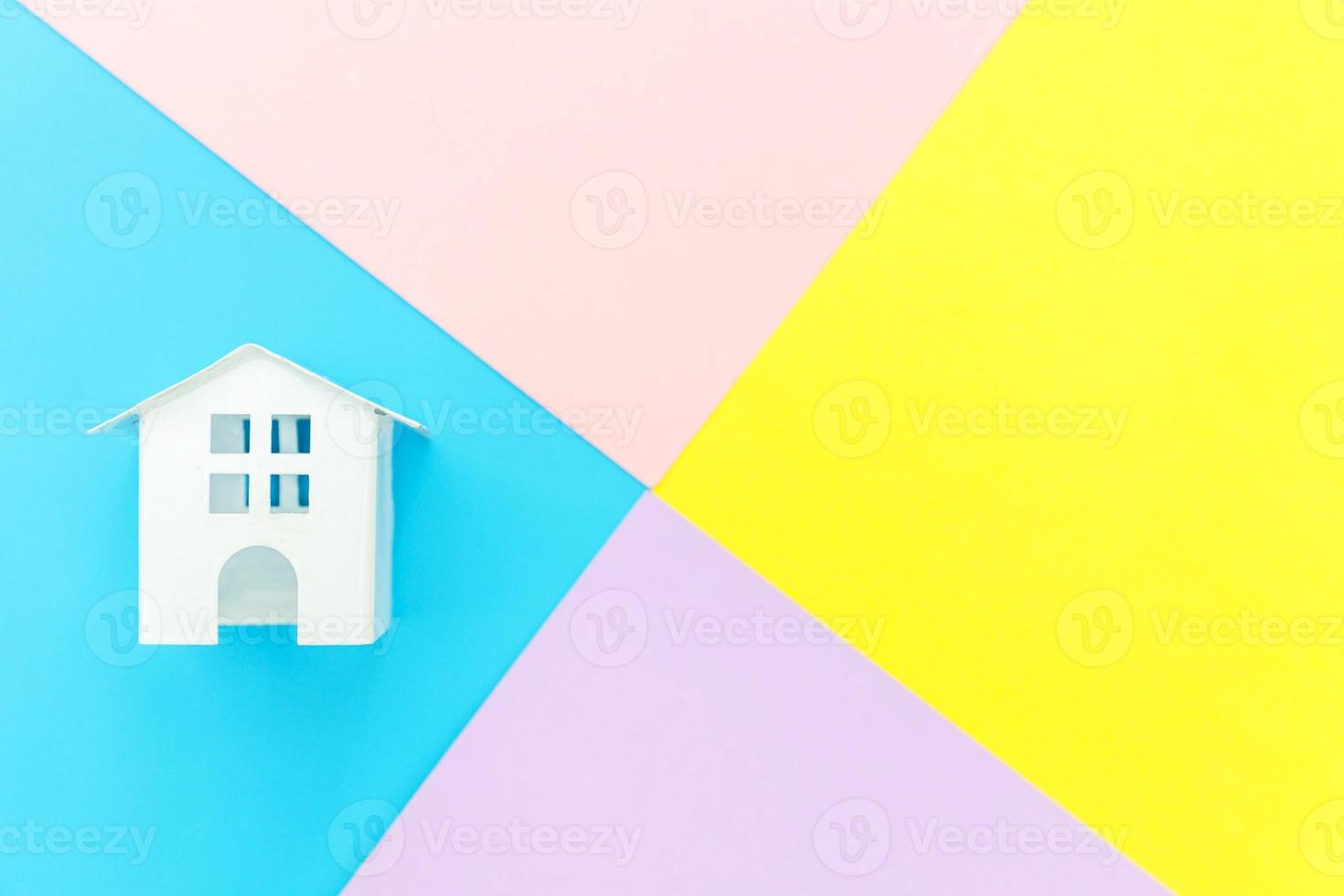 simplesmente projeto miniatura branco brinquedo casa isolado no azul amarelo rosa roxo pastel colorido na moda fundo geométrico hipoteca seguro propriedade sonho casa conceito. espaço de cópia de vista superior plana leiga. foto