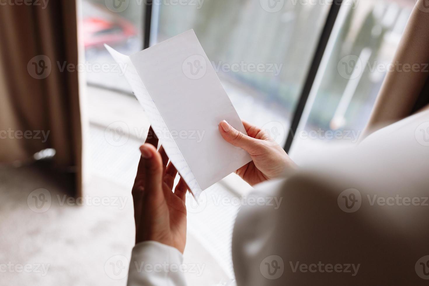 dia do casamento. taxas no hotel. a noiva perto da janela e lê a carta para o noivo. votos de casamento. preparações. manhã da noiva. noiva de vestido branco e véu. simular o espaço. foto