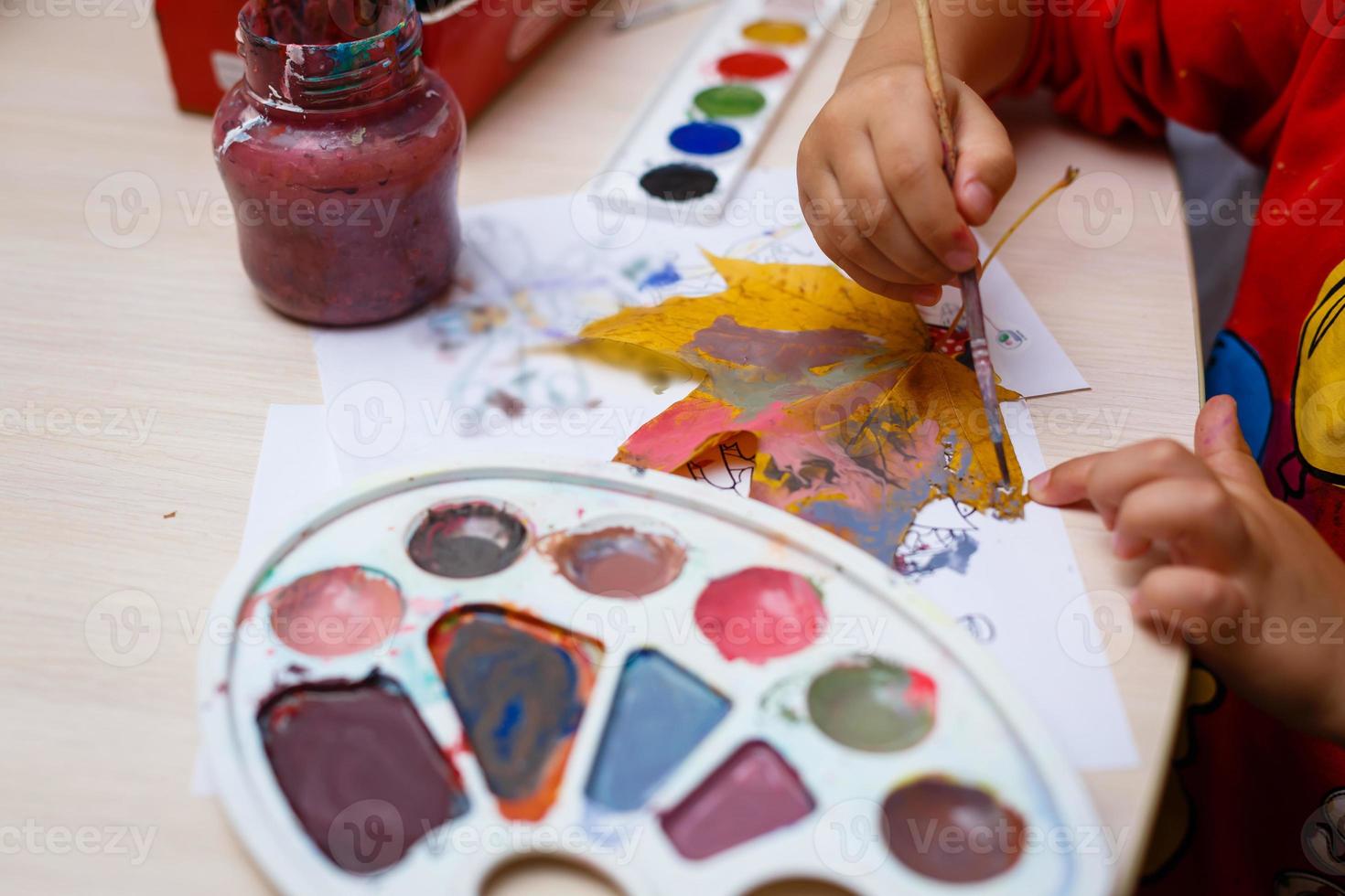 uma jovem linda está pintando a folha de bordo do outono foto