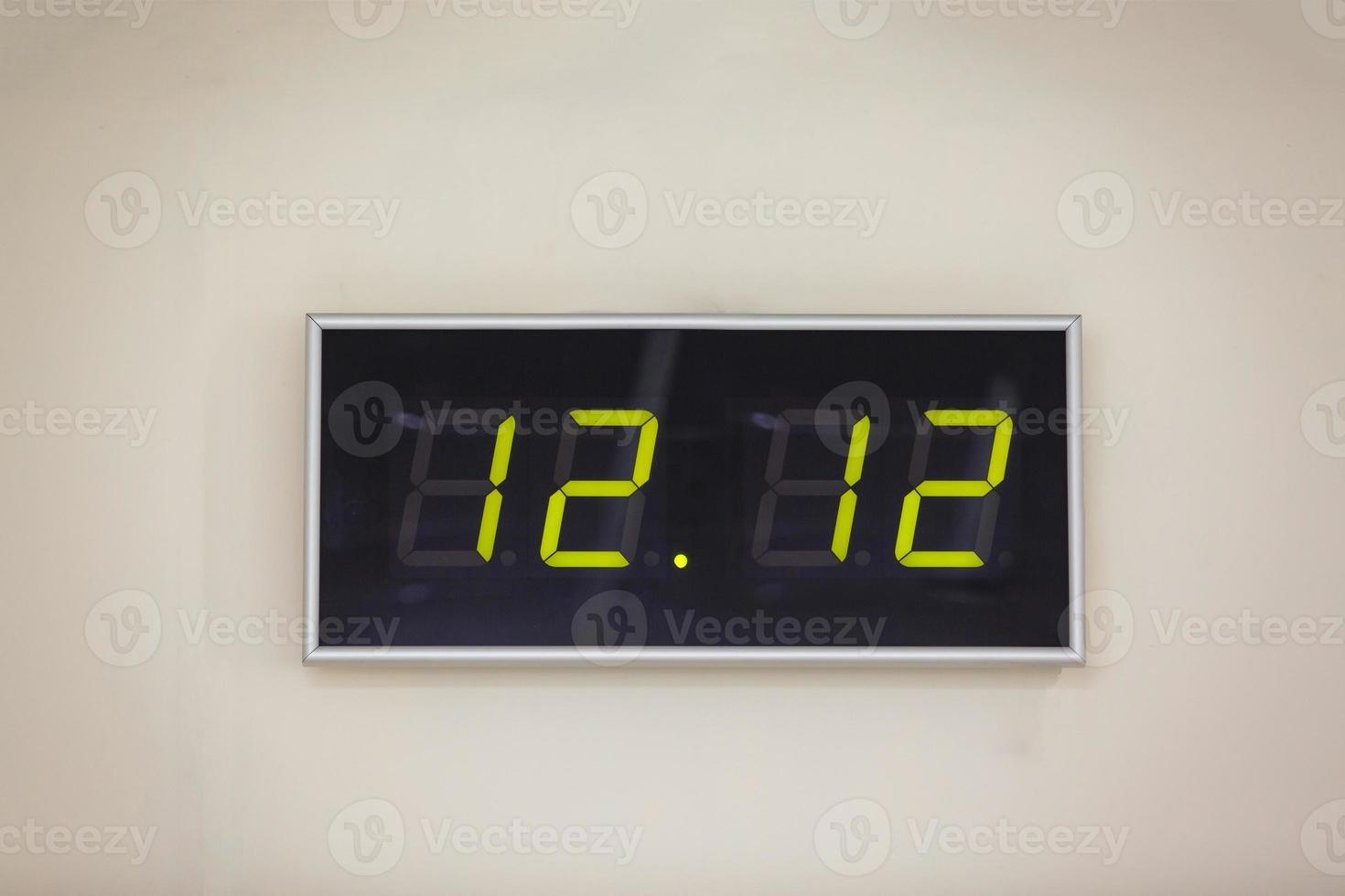 relógio digital preto sobre um fundo branco mostrando o tempo doze horas e doze minutos foto