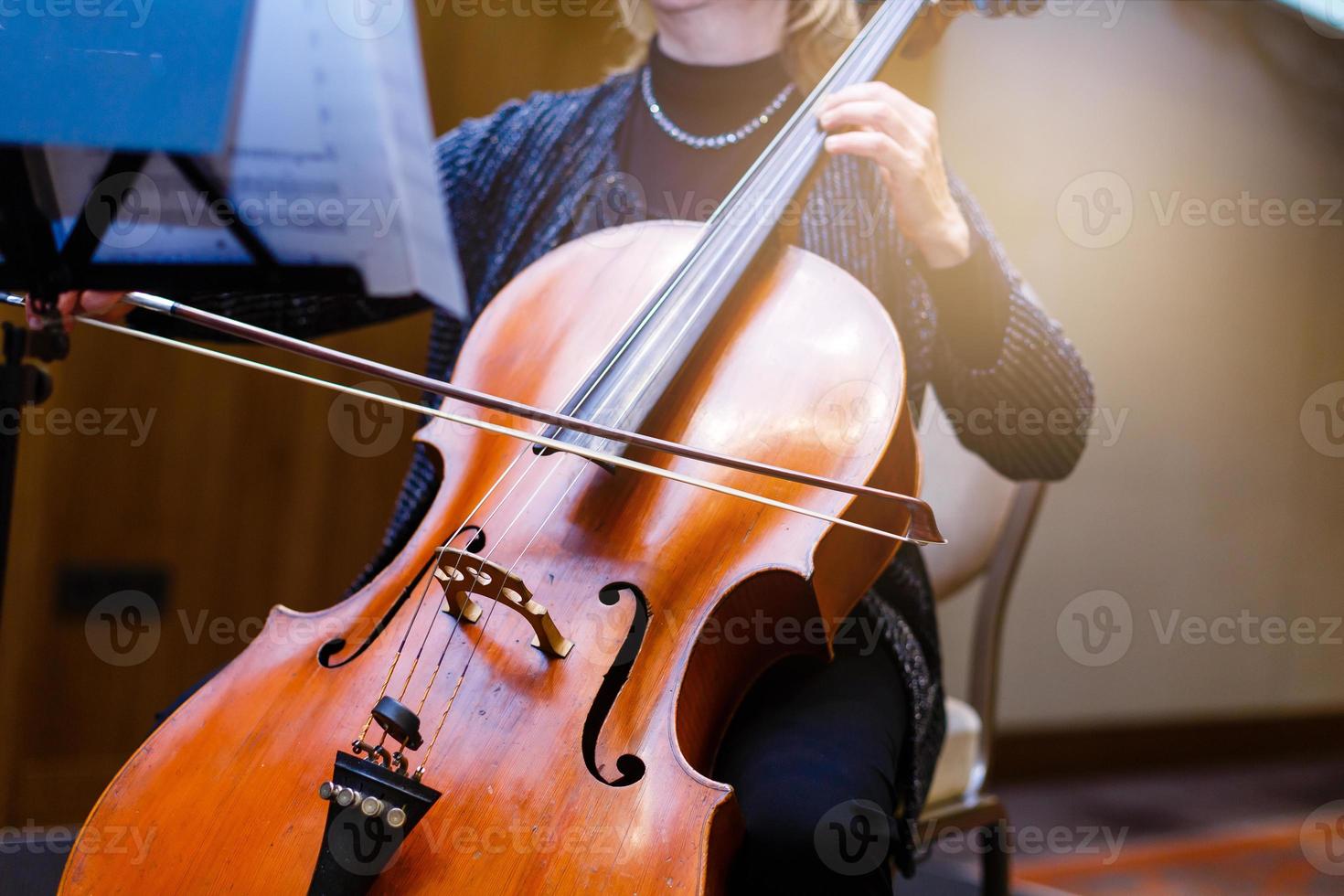 uma jovem toca violoncelo no escuro. mãos no violoncelo foto