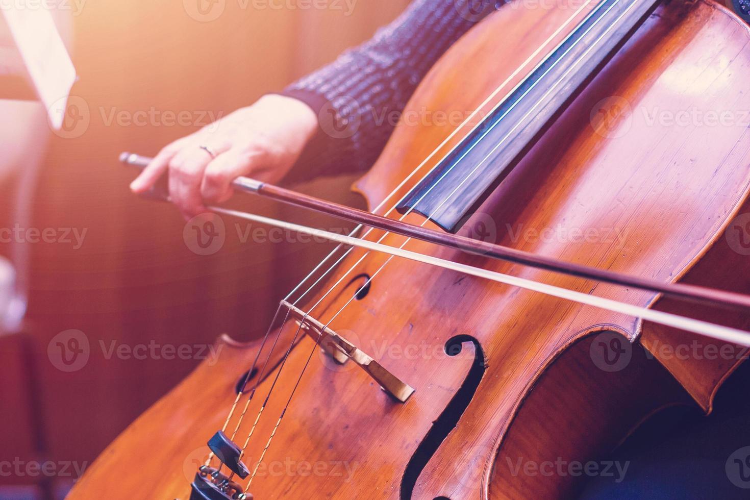 uma jovem toca violoncelo no escuro. mãos no violoncelo foto