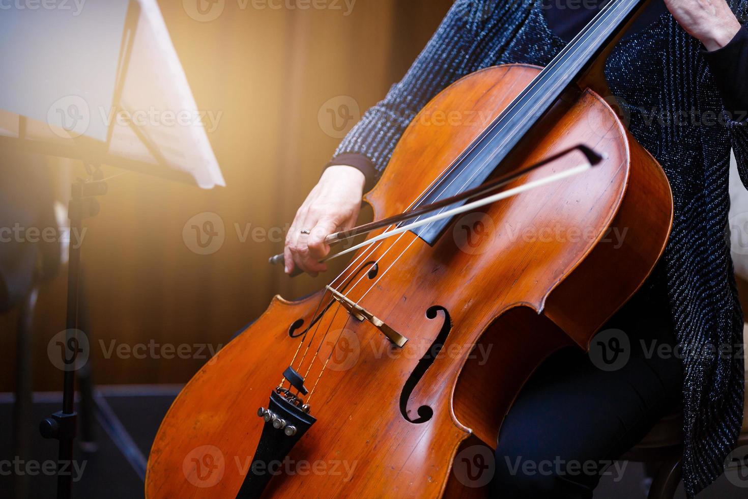 uma jovem toca violoncelo no escuro. mãos no violoncelo foto