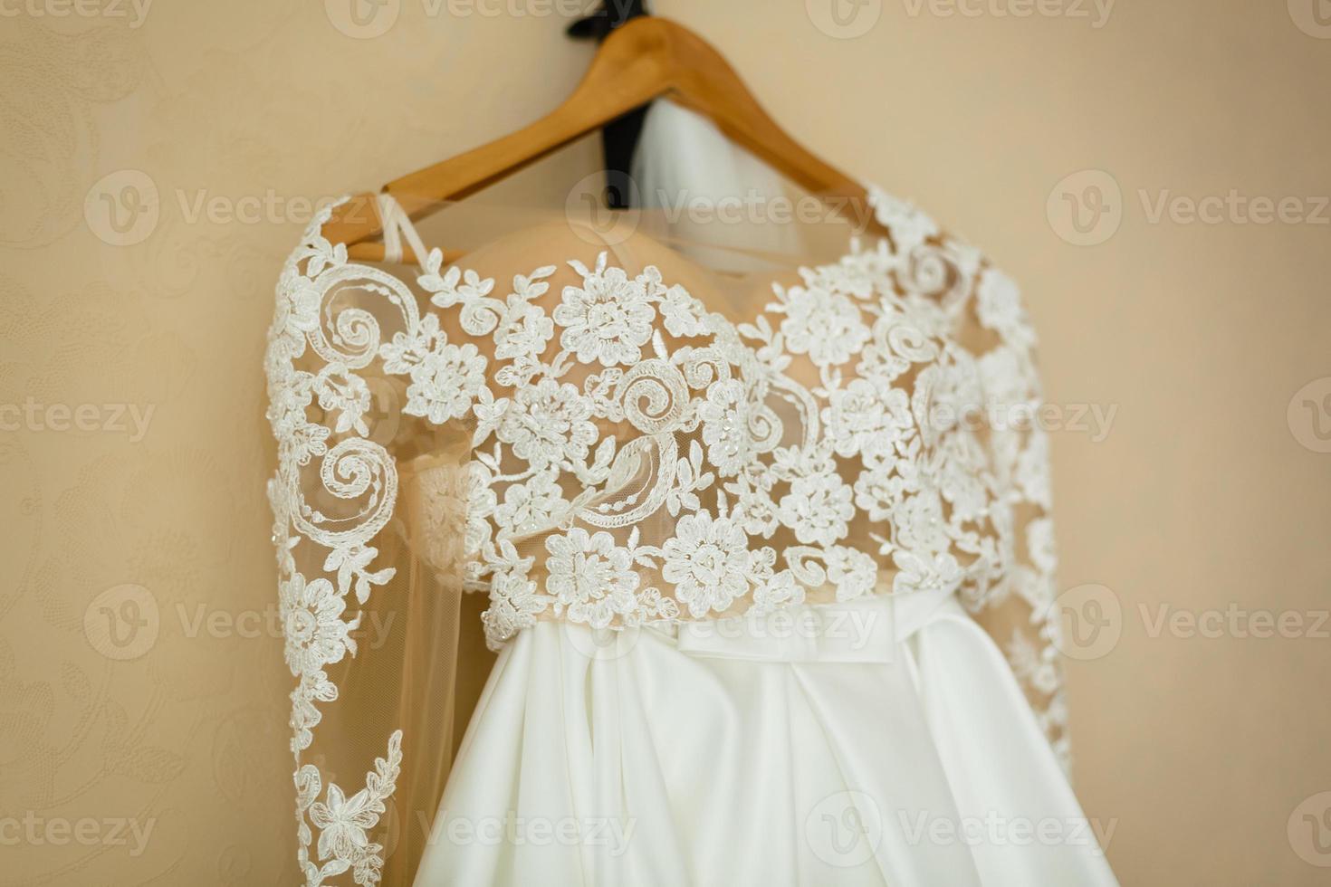 vestido de noiva de luxo com flores penduradas na janela de um quarto de hotel. vestido de noiva incrível moderno em luz. preparação matinal, preparando-se. espaço para texto. dia do casamento foto