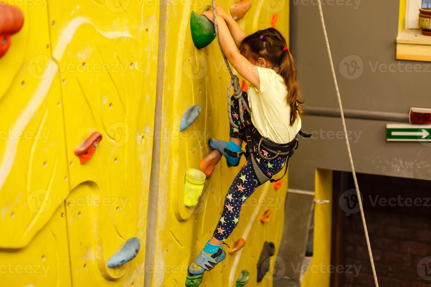 menina escalando uma parede de pedra interior foto