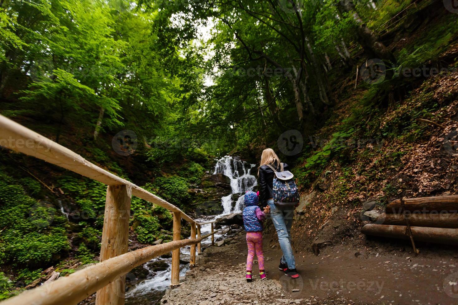 mãe e filha em pé perto da cachoeira foto