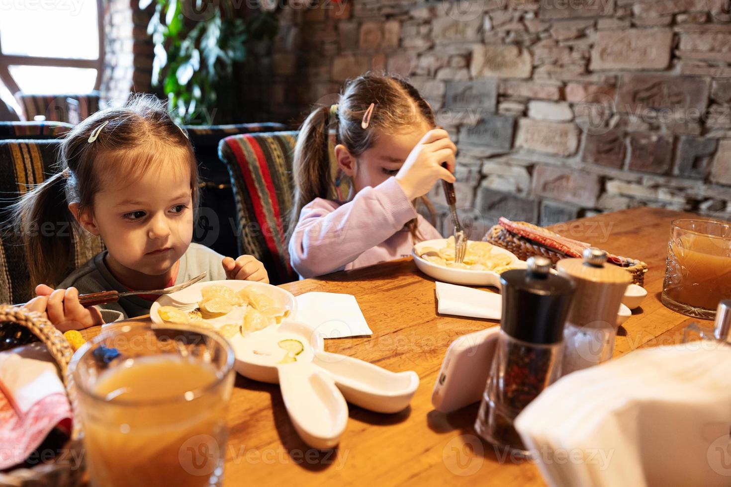 família tendo uma refeição juntos no autêntico restaurante ucraniano. as crianças das meninas comem bolinhos. foto